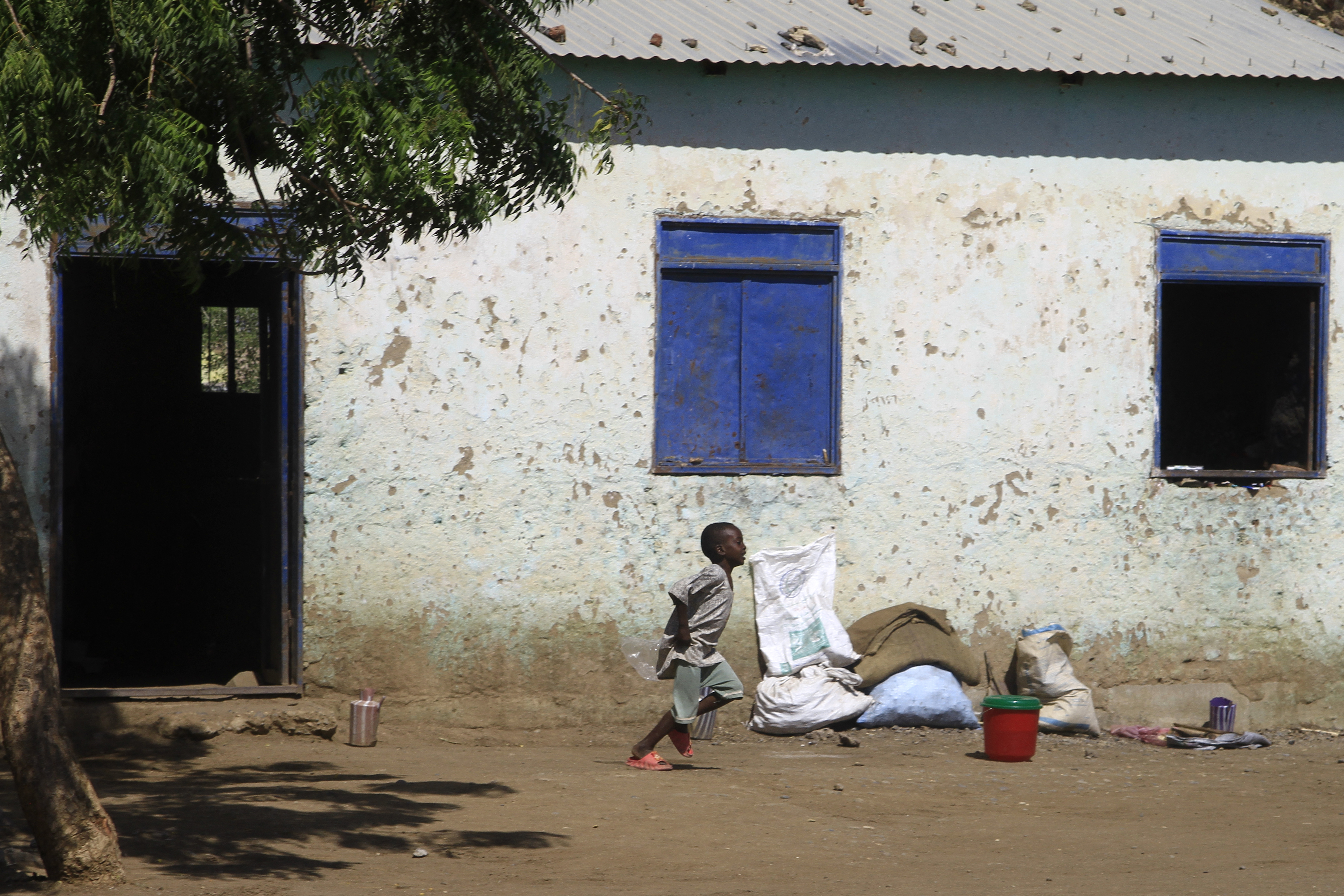 A child displaced from Sudan's Jazira state runs in front of a temporary shelter in Gedaref in the country's east on December 28, 2023. - The rapid advance of Sudanese paramilitaries has intensified calls on civilians to carry arms, raising the spectre of the eight-month conflict between rival generals transforming into full-blown civil war. (Photo by AFP)