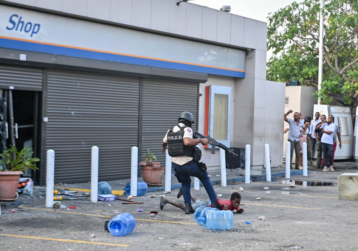 Haitian policeman kicks a child
