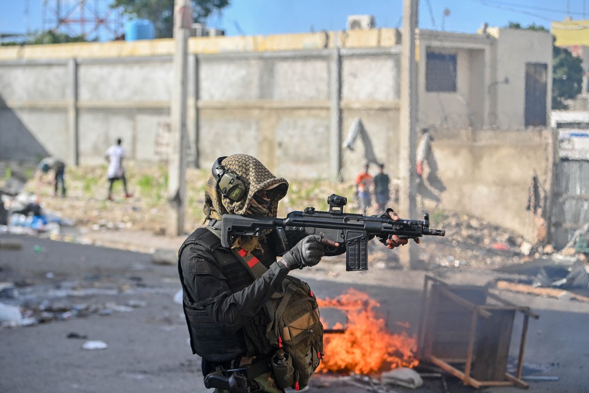 A policeman points a gun at protesters