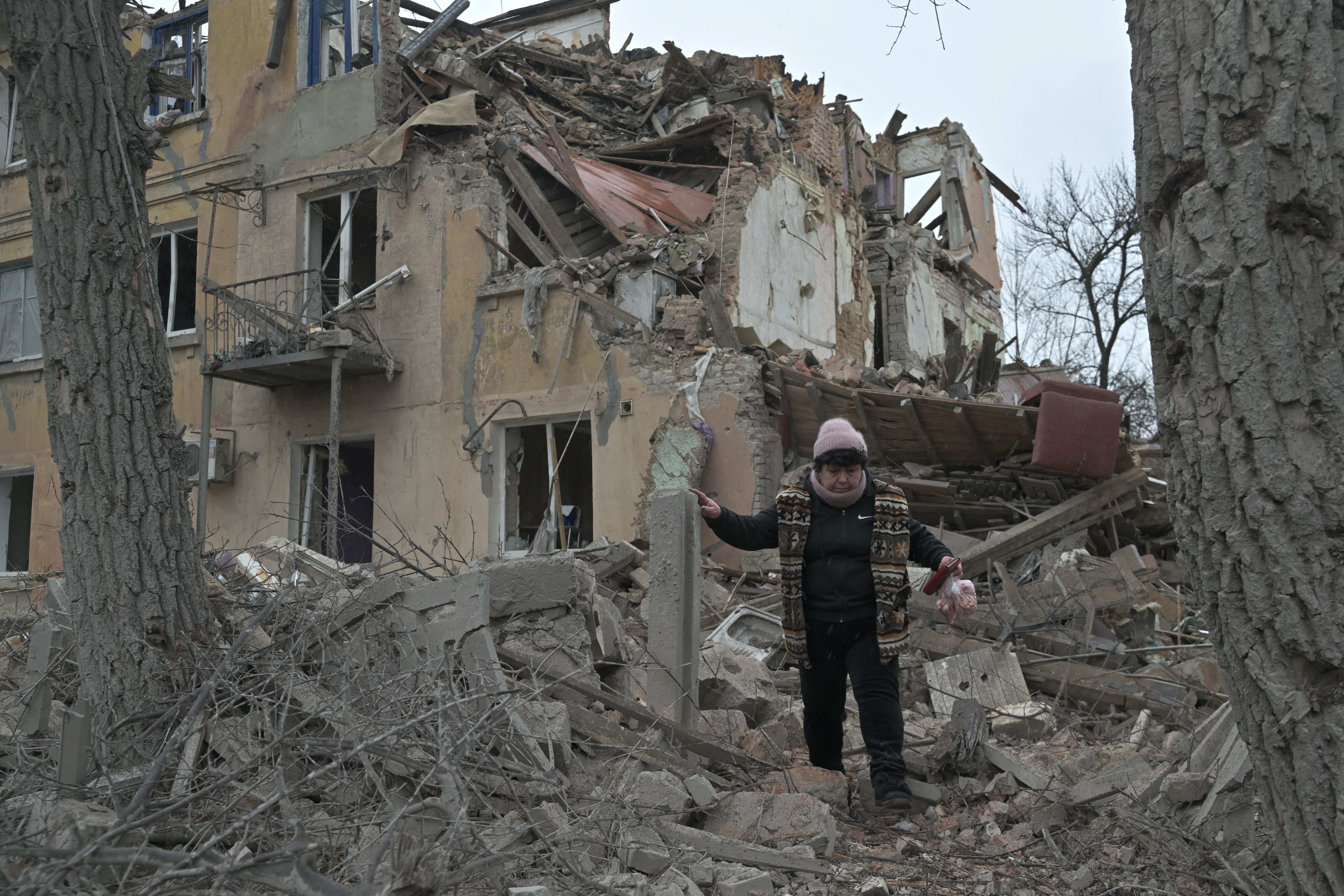 A woman walking through debris from a damaged building