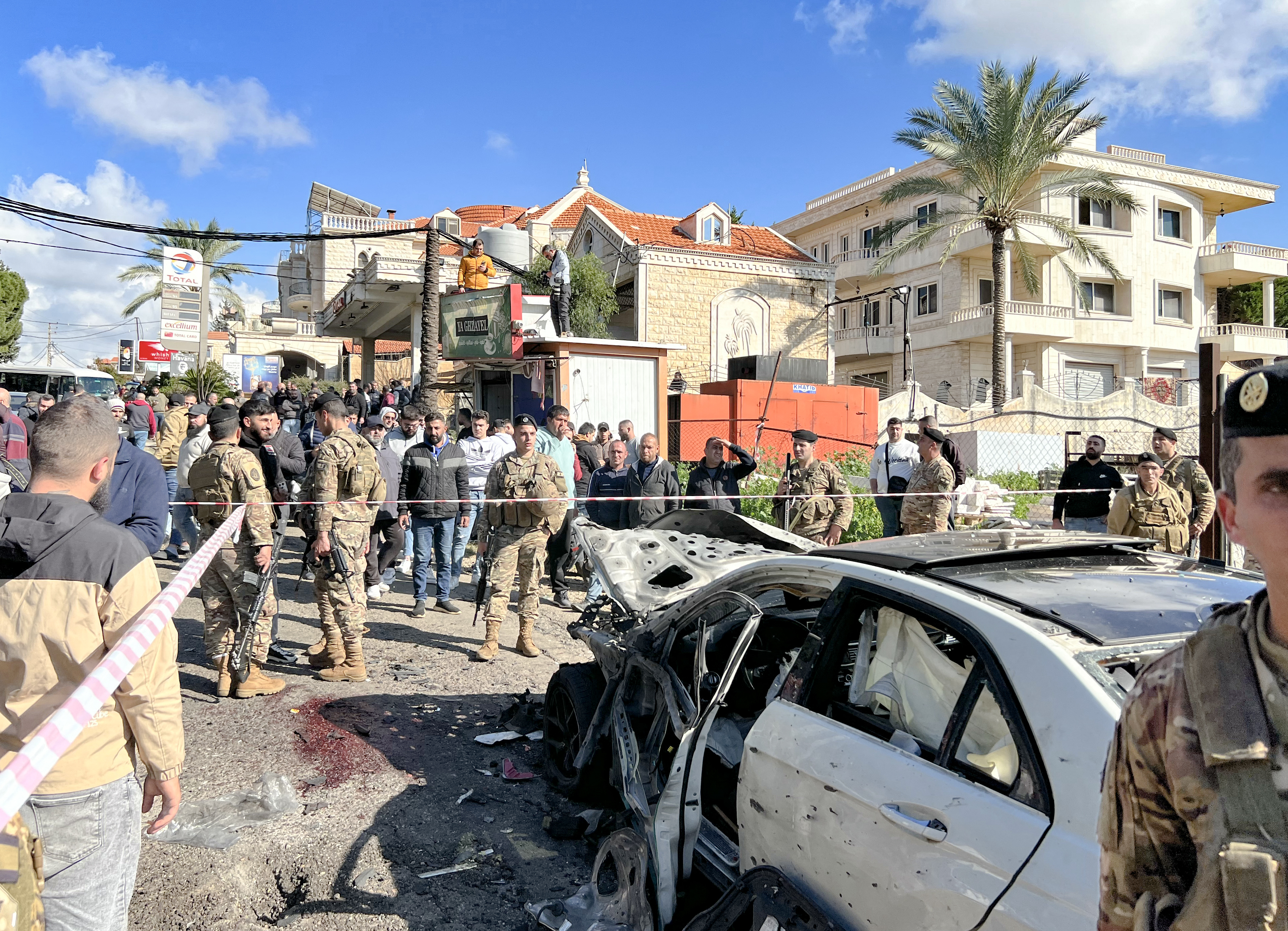 Blood stains cover the ground next to a a car wrecked in a reported Israeli drone attack, as Lebanese army soldiers secure the area in the village of Jadra between Beirut and the southern city of Sidon