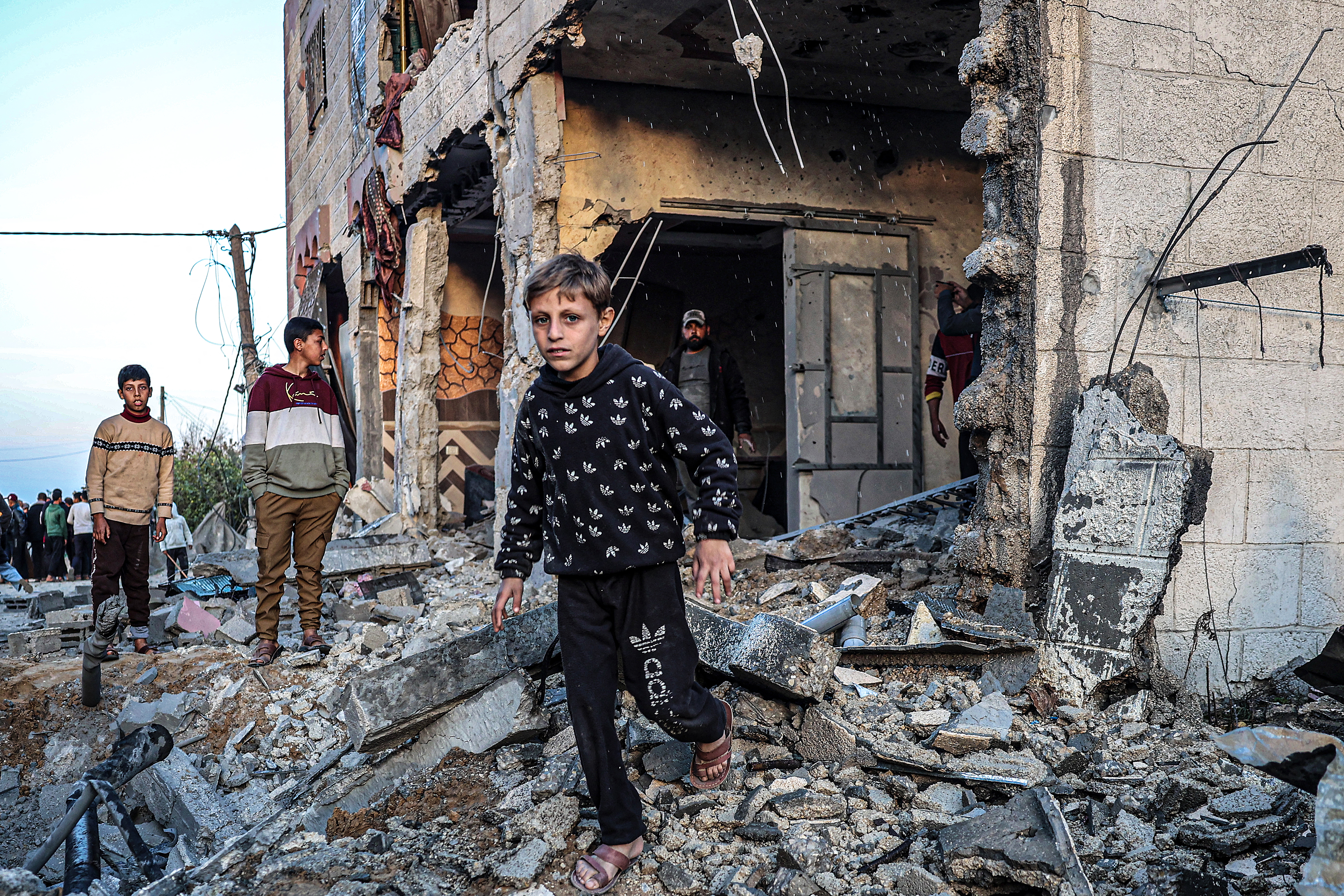 People walk through the rubble of a building heavily damaged by Israeli bombardment, in Rafah in the southern Gaza Strip on February 11, 2024, amid the ongoing conflict between Israel and the Palestinian militant group Hamas. (Photo by SAID KHATIB / AFP)