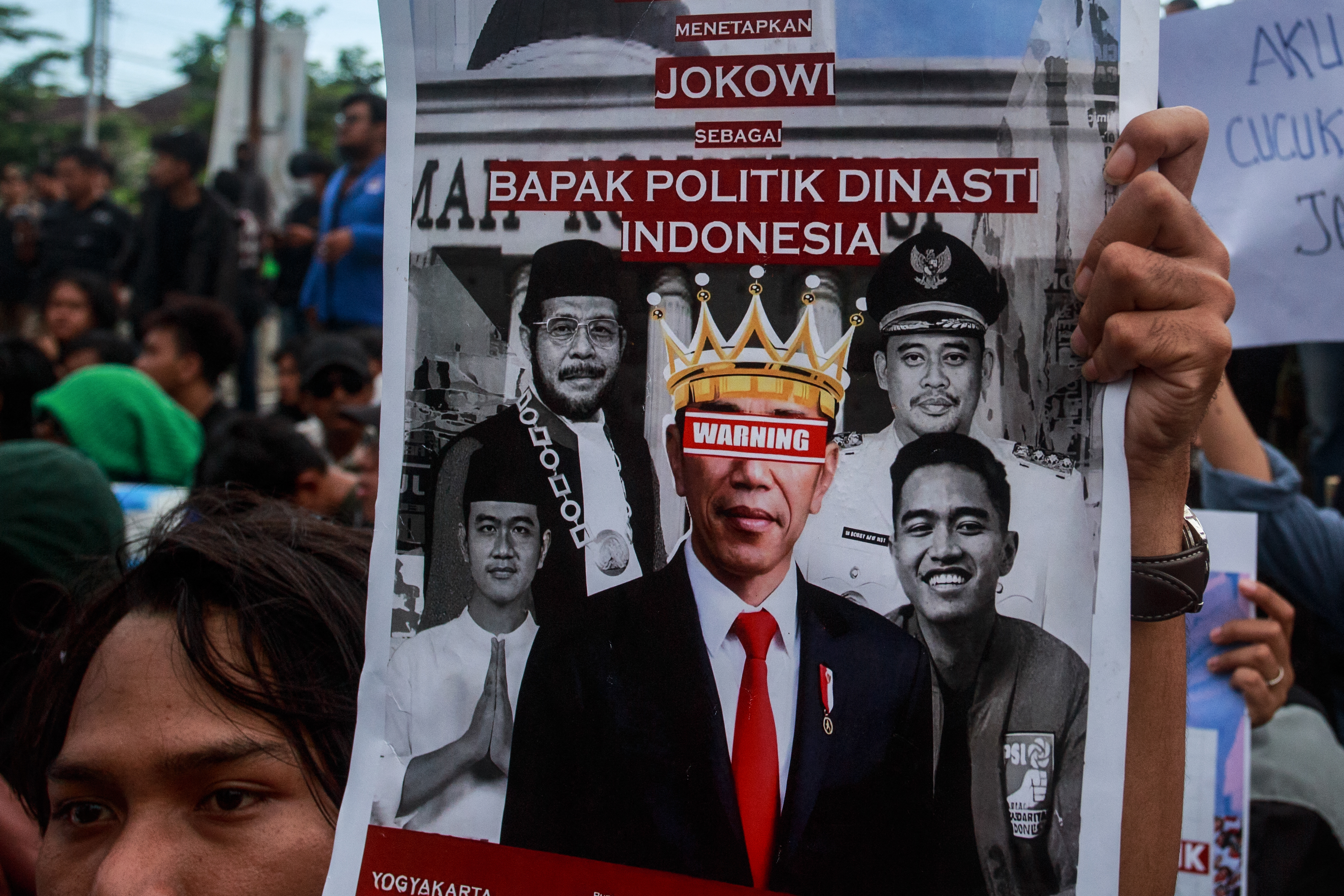 A protester holding up a placard showing photos of Jokowi and his family members and condemning for creating a dynasty