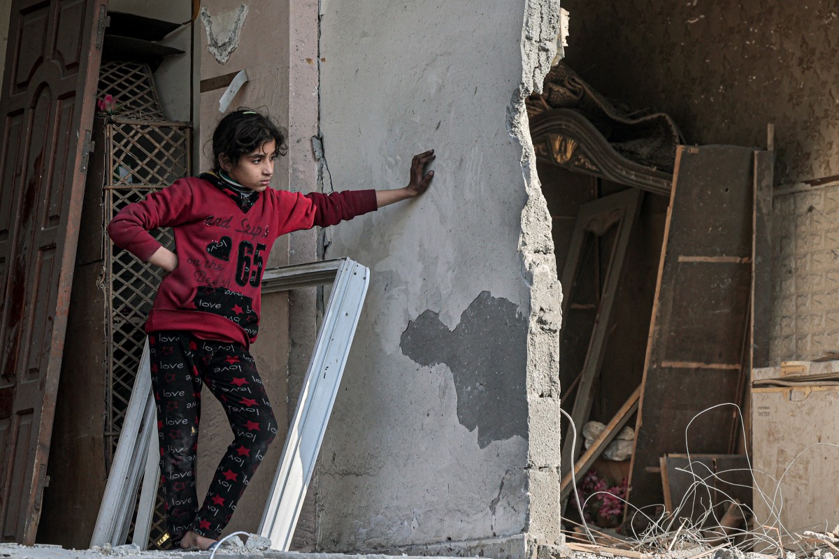 A Palestinian girl looks on as she stands in a damaged building