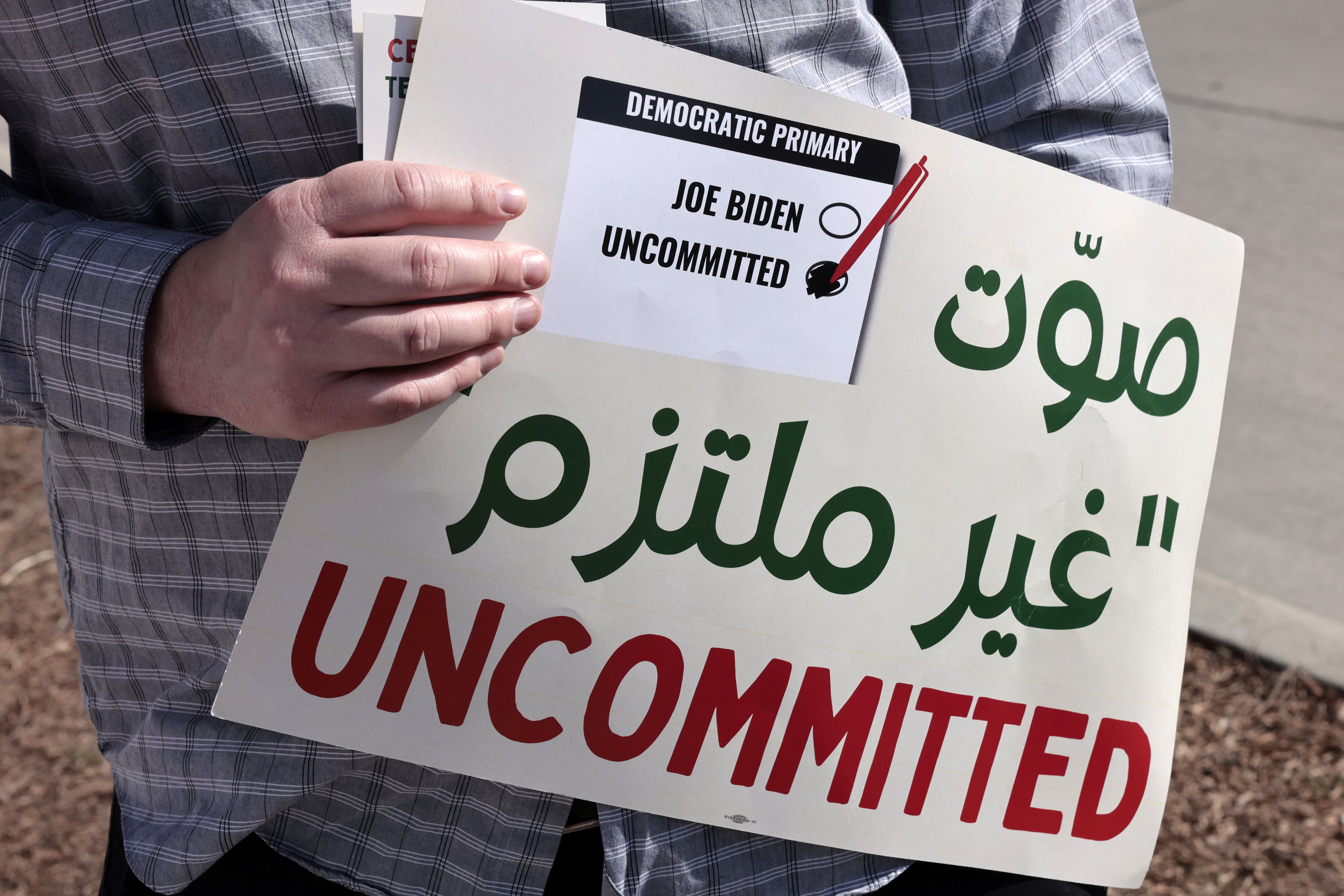 A volunteer holds a sign asking people to vote uncommitted, instead of for US President Joe Biden, outside of Maples School in Dearborn, Michigan 2024 in the US Presidential primary election in Dearborn, Michigan on February 27, 2024.