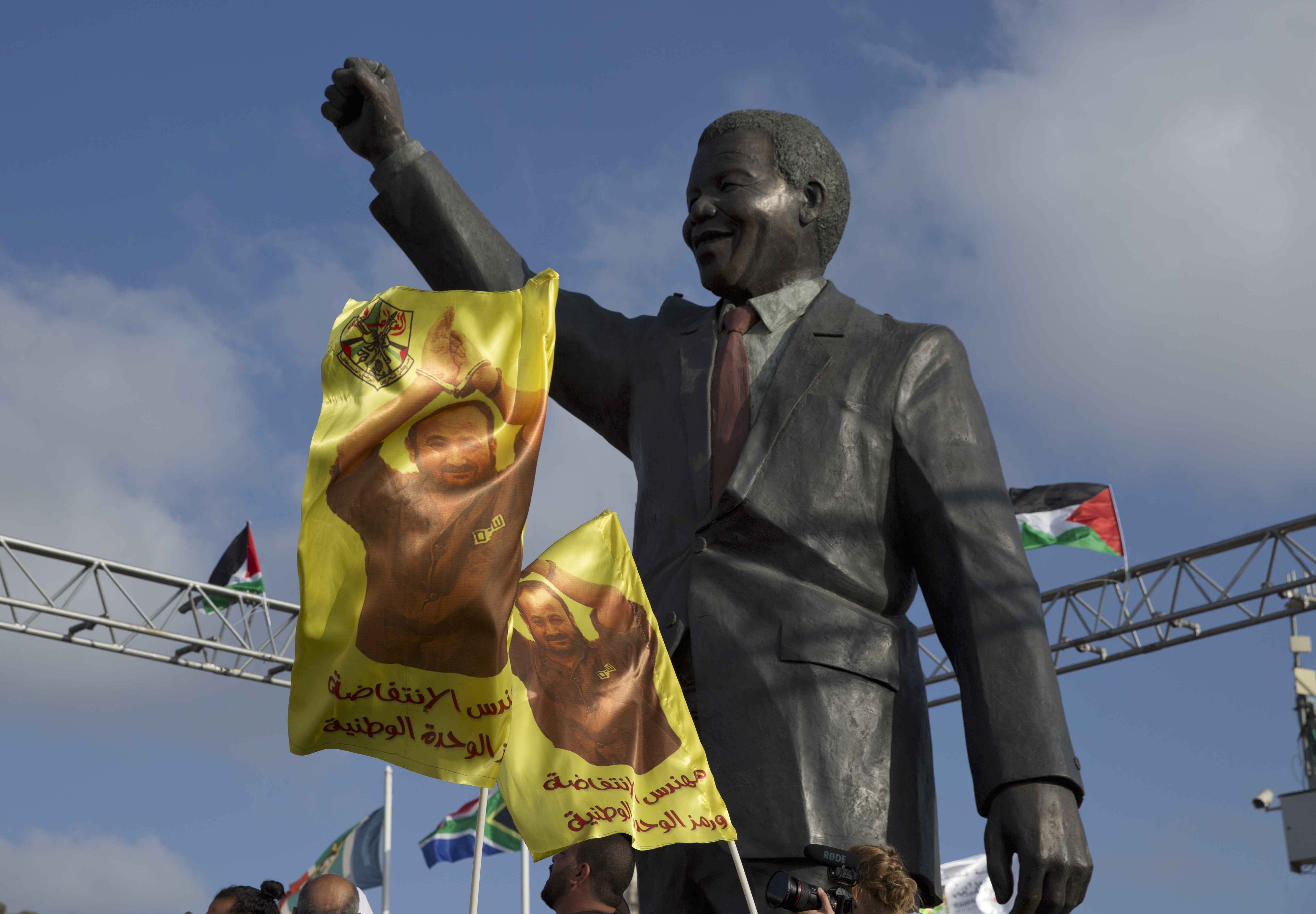 Protesters wave banners with a picture of jailed Palestinian uprising leader Marwan Barghouti under a statue of Nelson Mandela, during a rally supporting hunger striking Palestinian prisoners in Israeli jails, who have been on an open-ended hunger strike for the past 17 days, in the West Bank city of Ramallah, Wednesday, May 3, 2017. The prisoners launched the protest to press for better conditions, including family visits. Arabic reads "the uprising engineer and the symbol of national unity."