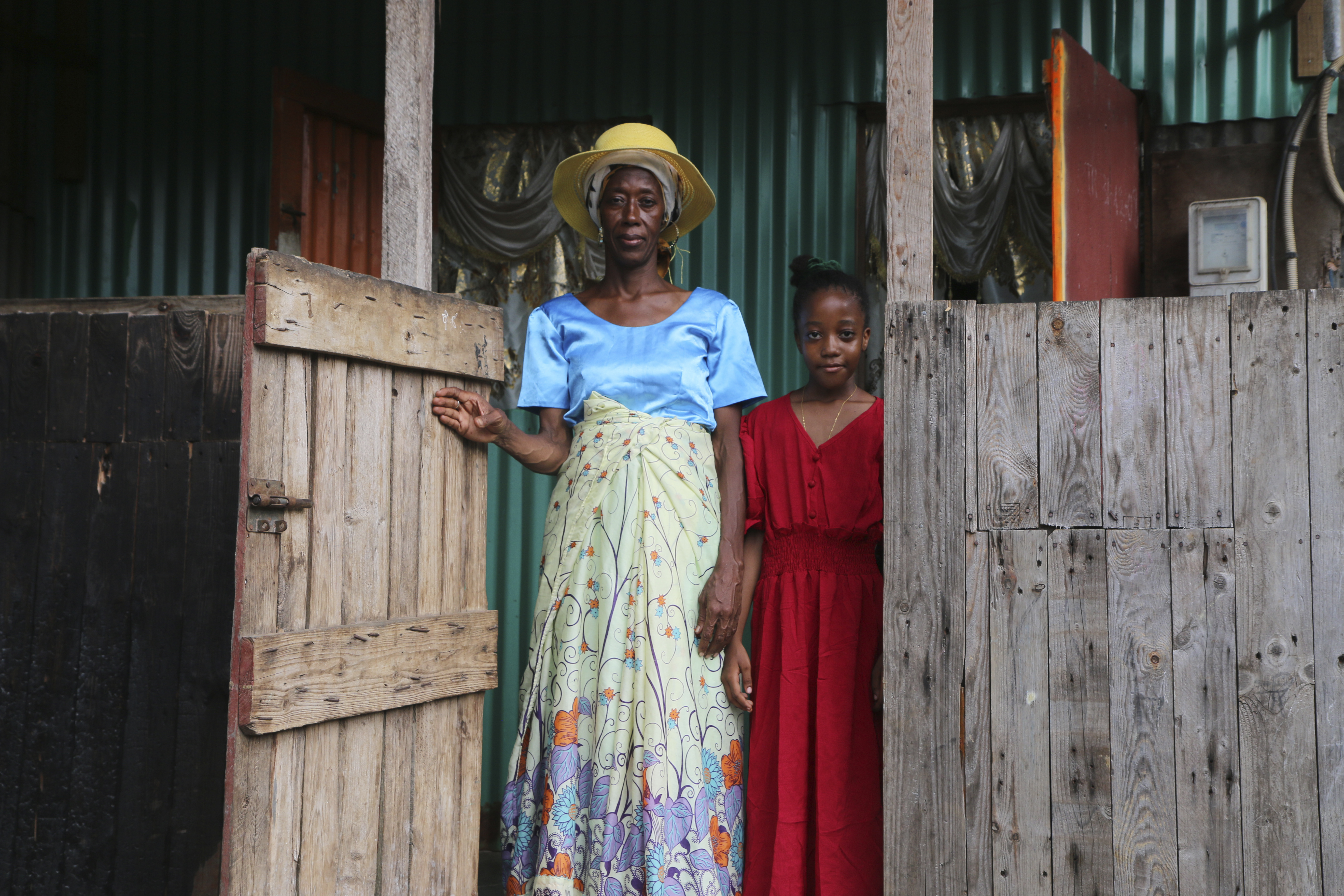 Zenabou S, a Comoros woman married to a French man in Mayotte and her French daughter, stand at their door step as they prepare to move, in the Talus 2 district of Koungou, in the French Indian Ocean territory of Mayotte Saturday,