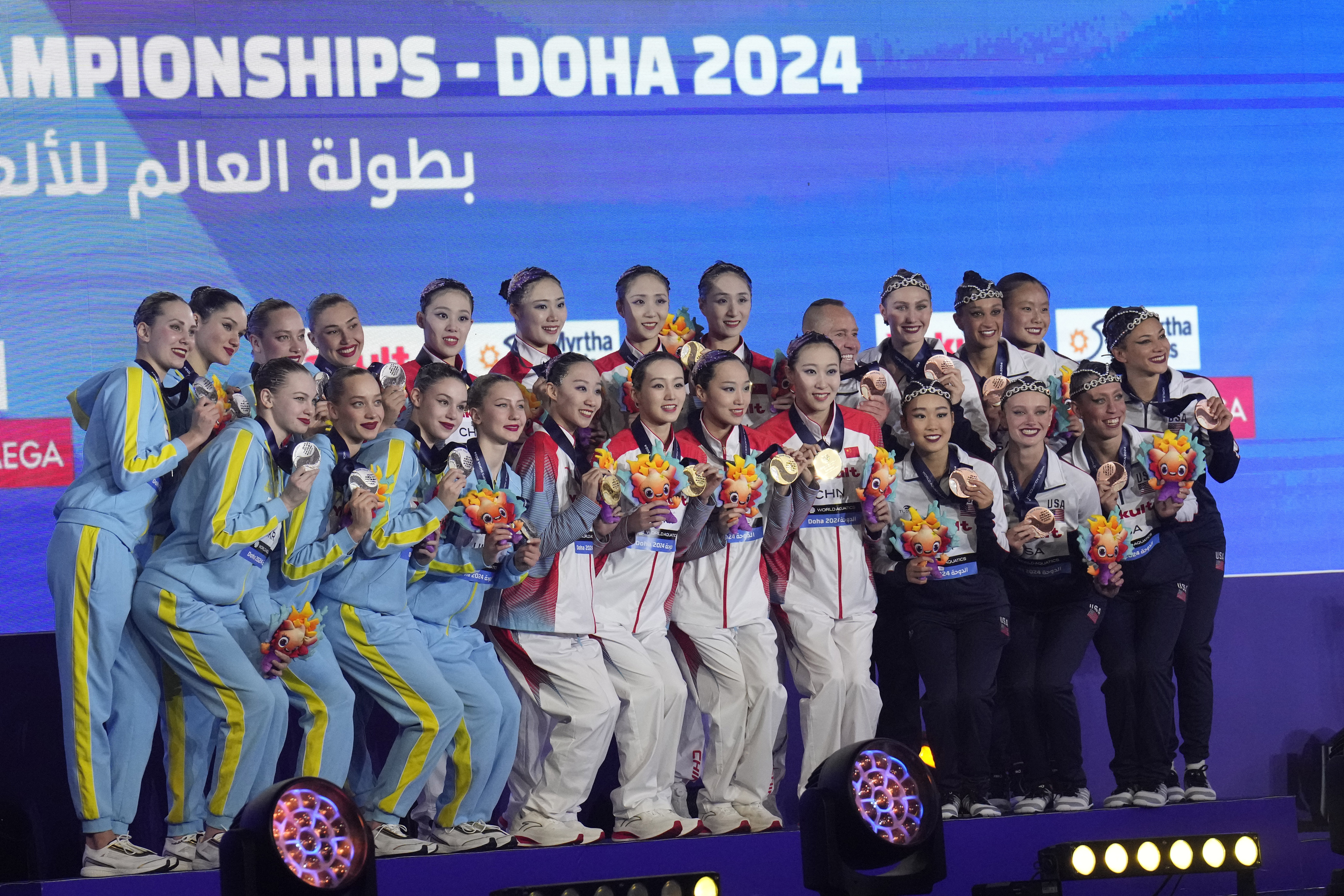 Gold medalists China team, center, silver medalists Ukraine team, left, bronze medalists United States team, right, pose with their medals during the medal ceremony for the mixed team acrobatic final of artistic swimming at the World Aquatics Championships in Doha, Qatar, Sunday, Feb. 4