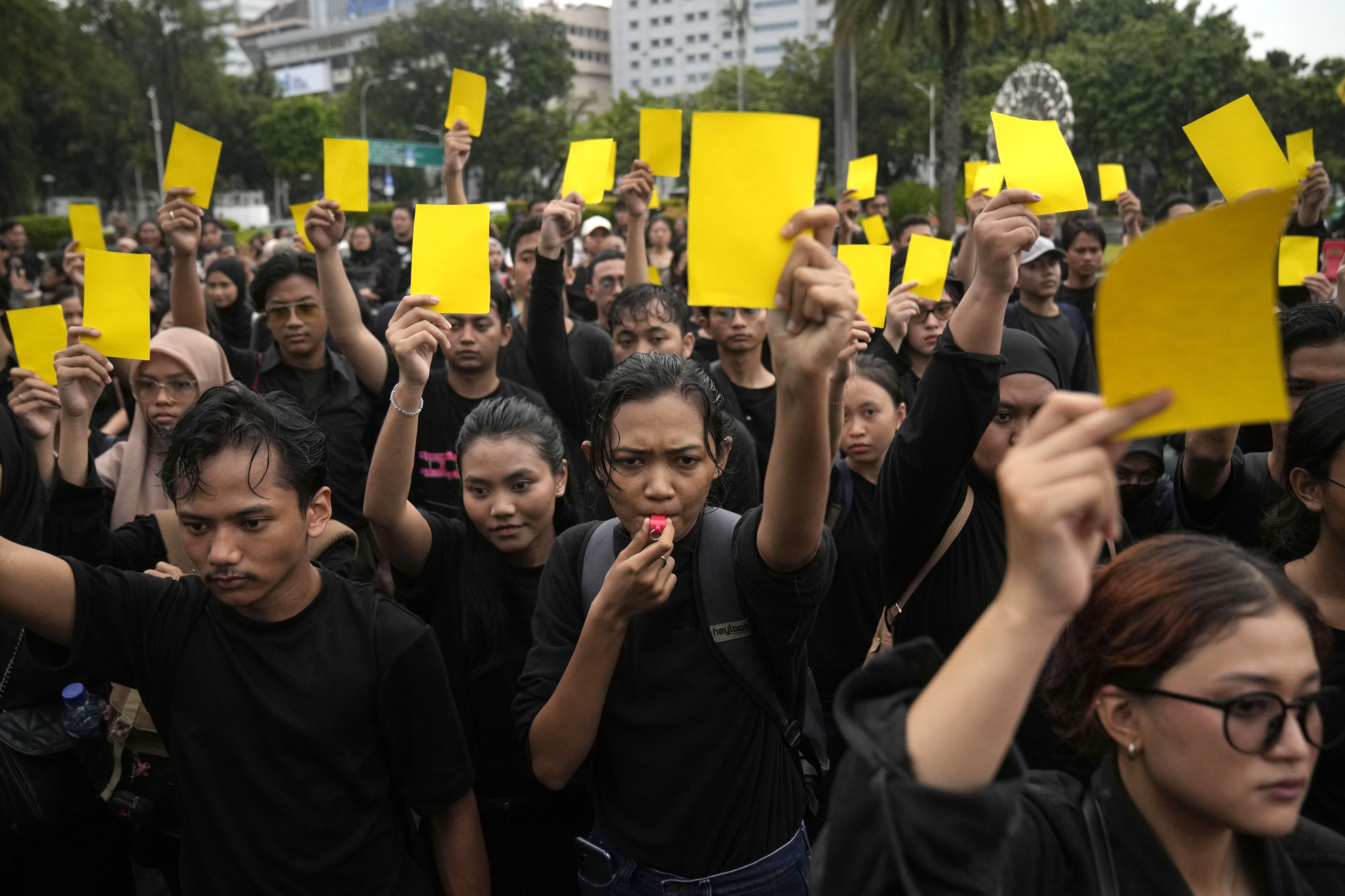 Protesters showing a 'yellow card' for Jokowi after the election. They are all wearing black.