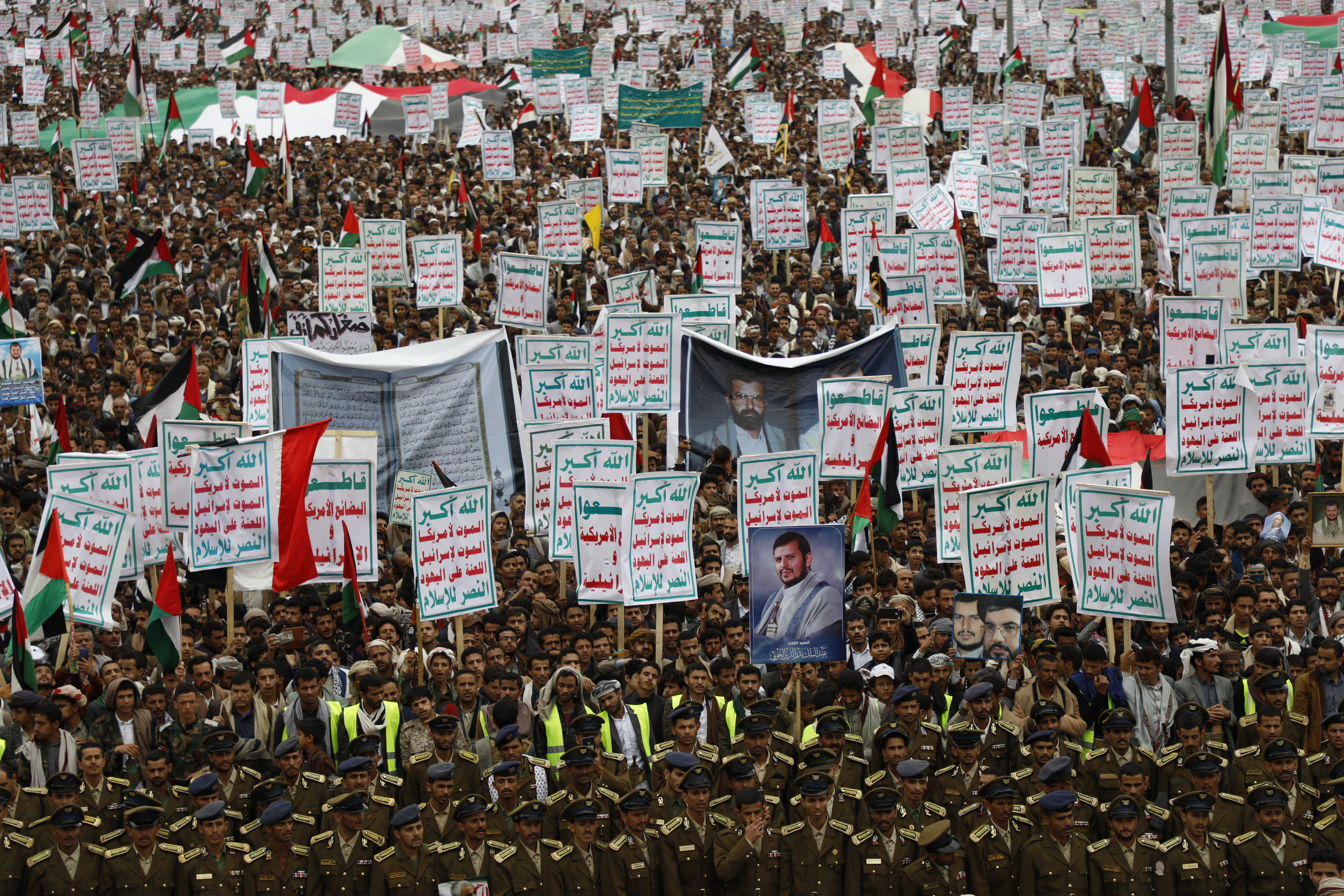 a large crowd waves Palestinian flags