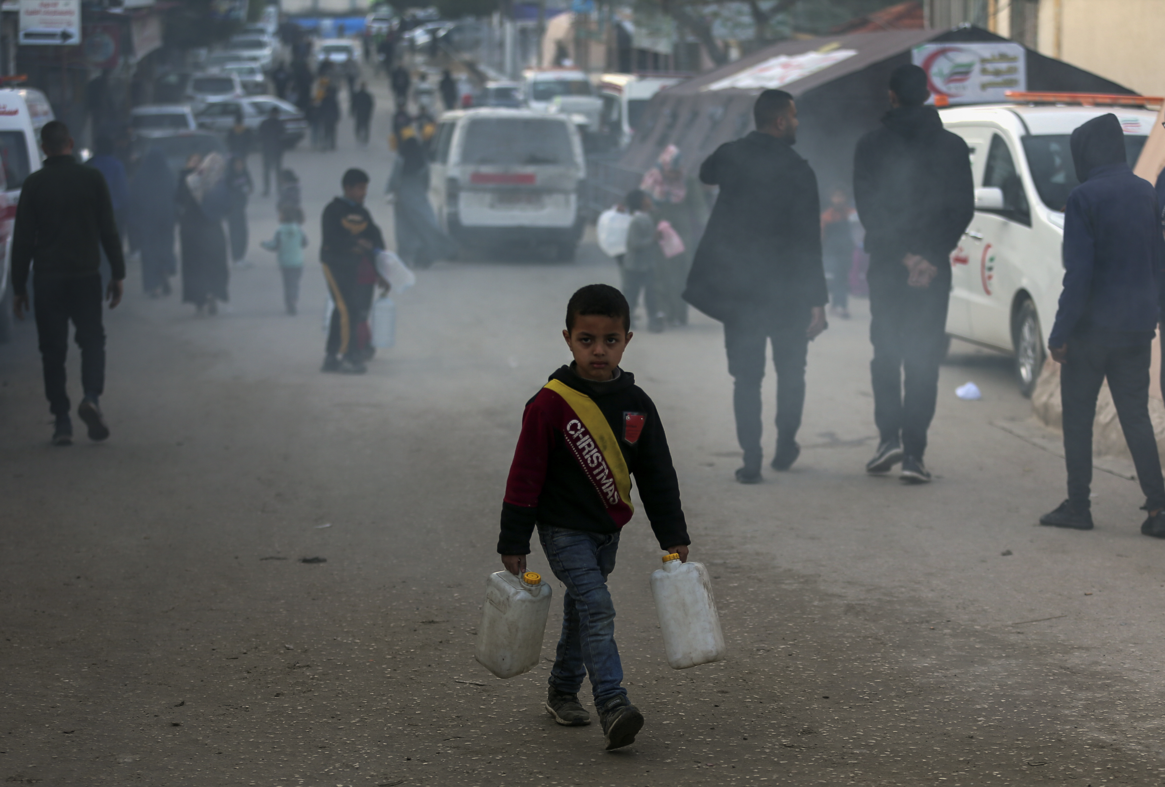 A Palestinian child displaced by the Israeli ground offensive on the Gaza Strip carries jerry cans at a makeshift tent camp in Rafah