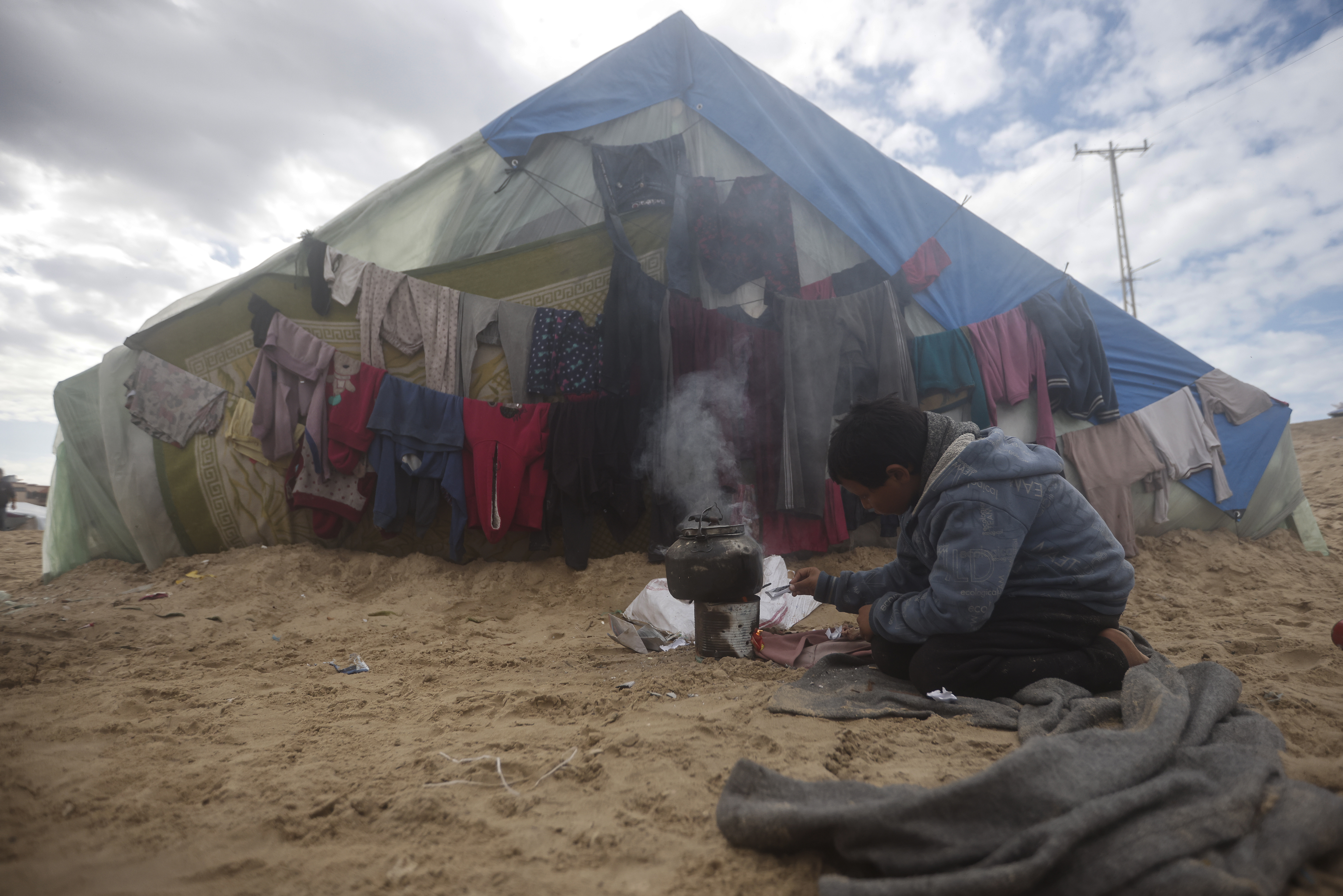 A Palestinian child displaced by the Israeli ground offensive on the Gaza Strip makes tea at a makeshift tent camp in Rafah
