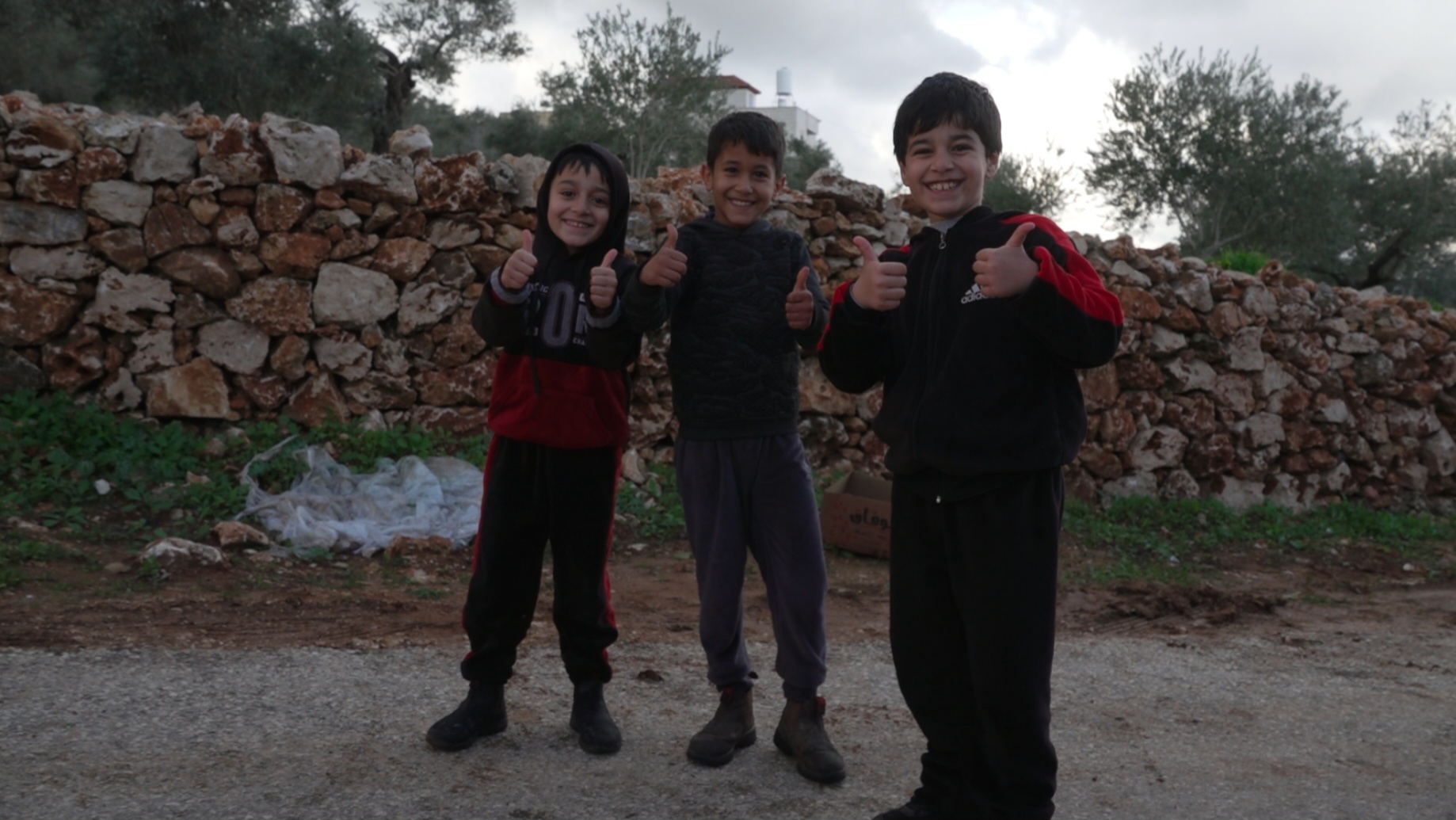 Three small boys flashing grins and thumbs-ups