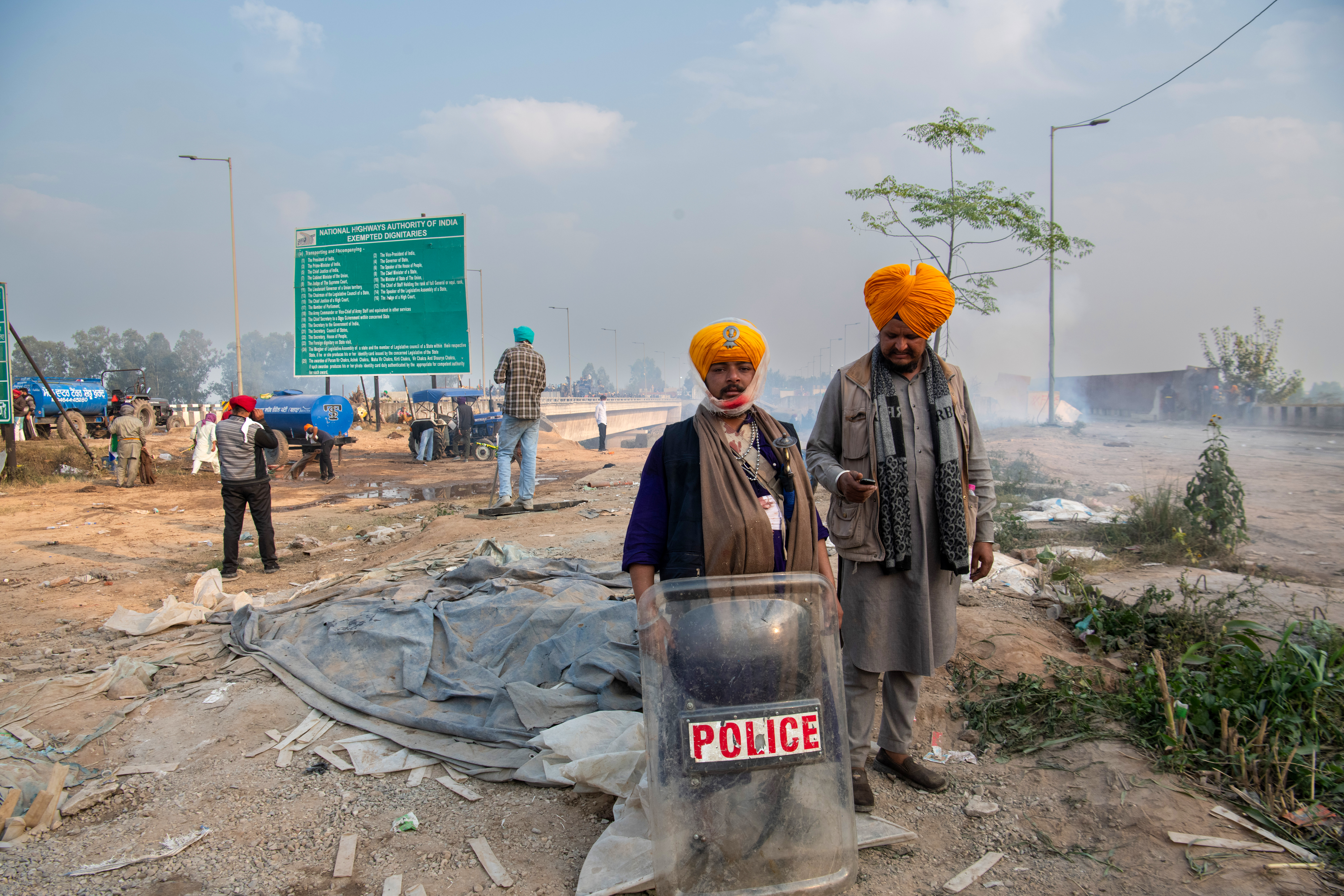 A farmer poses with a police shield left behind during the lathi charge on the protesting farmers at the Sindhu border, aimed at preventing them from entering Delhi. Several farmers suffer injuries after being beaten by police at the border.