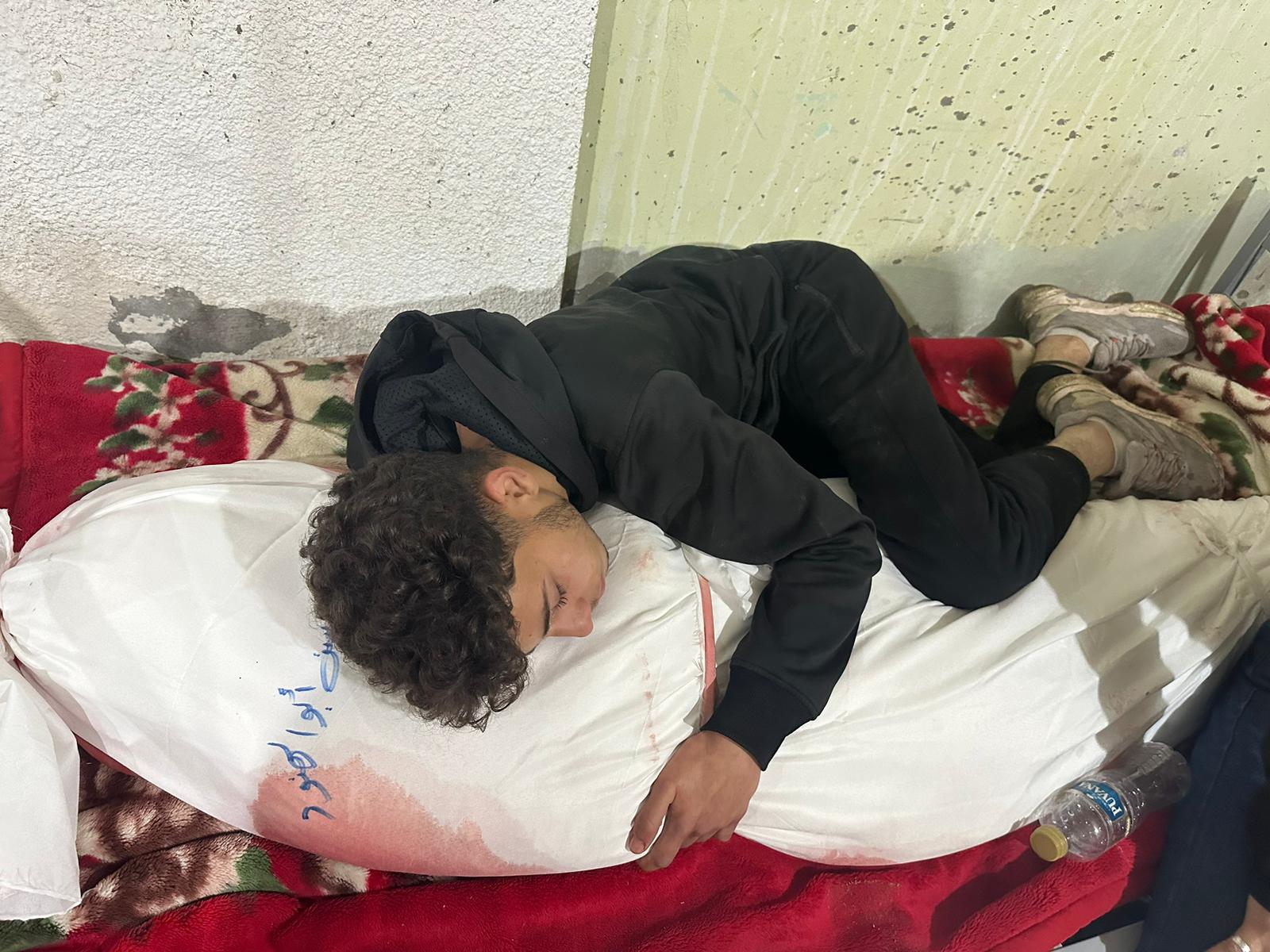 Ahmed curled up, holding the shrouded bloodied body of his mother
