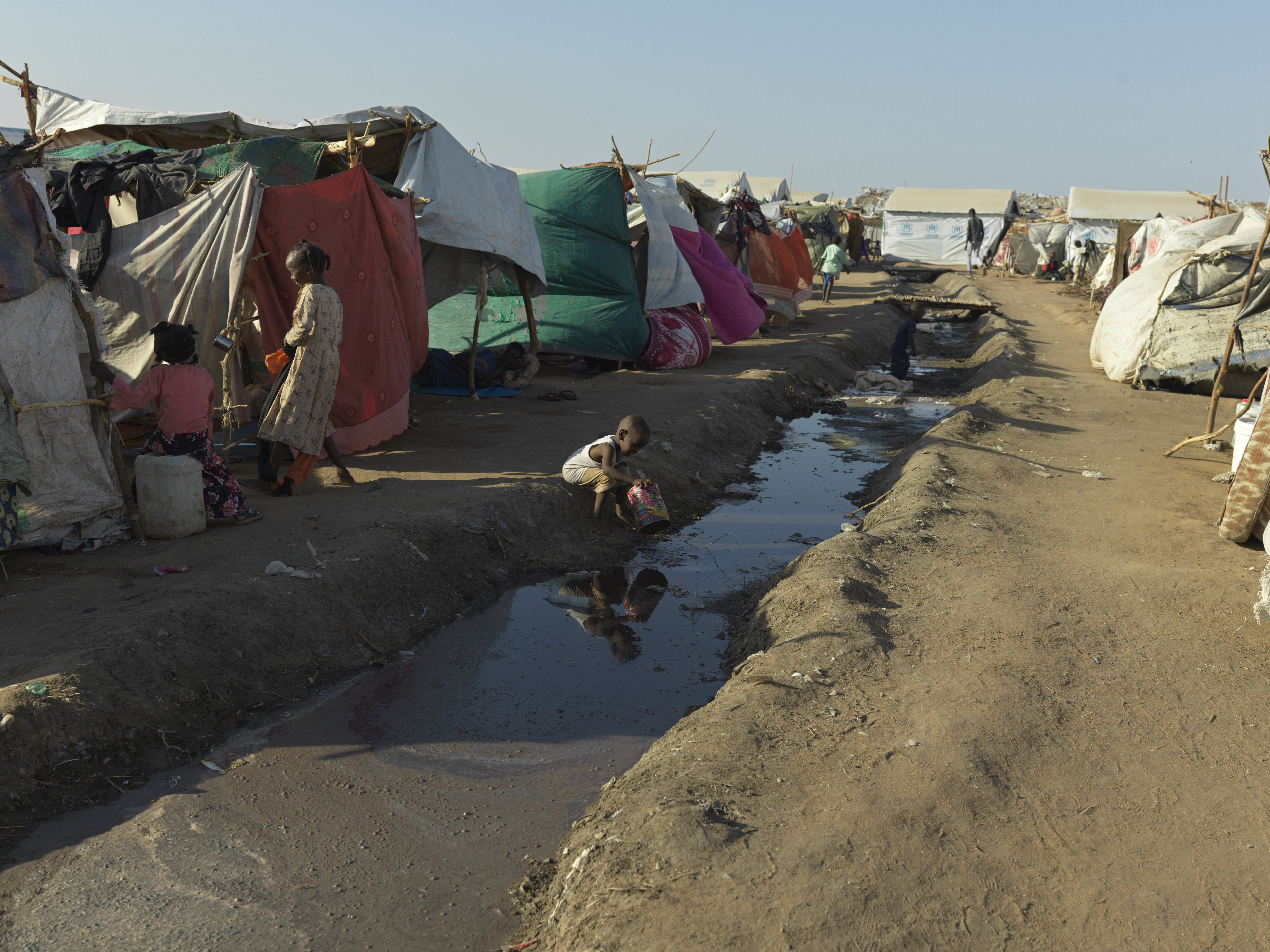 A child plays in an open sewer at the transit centre in Renk.