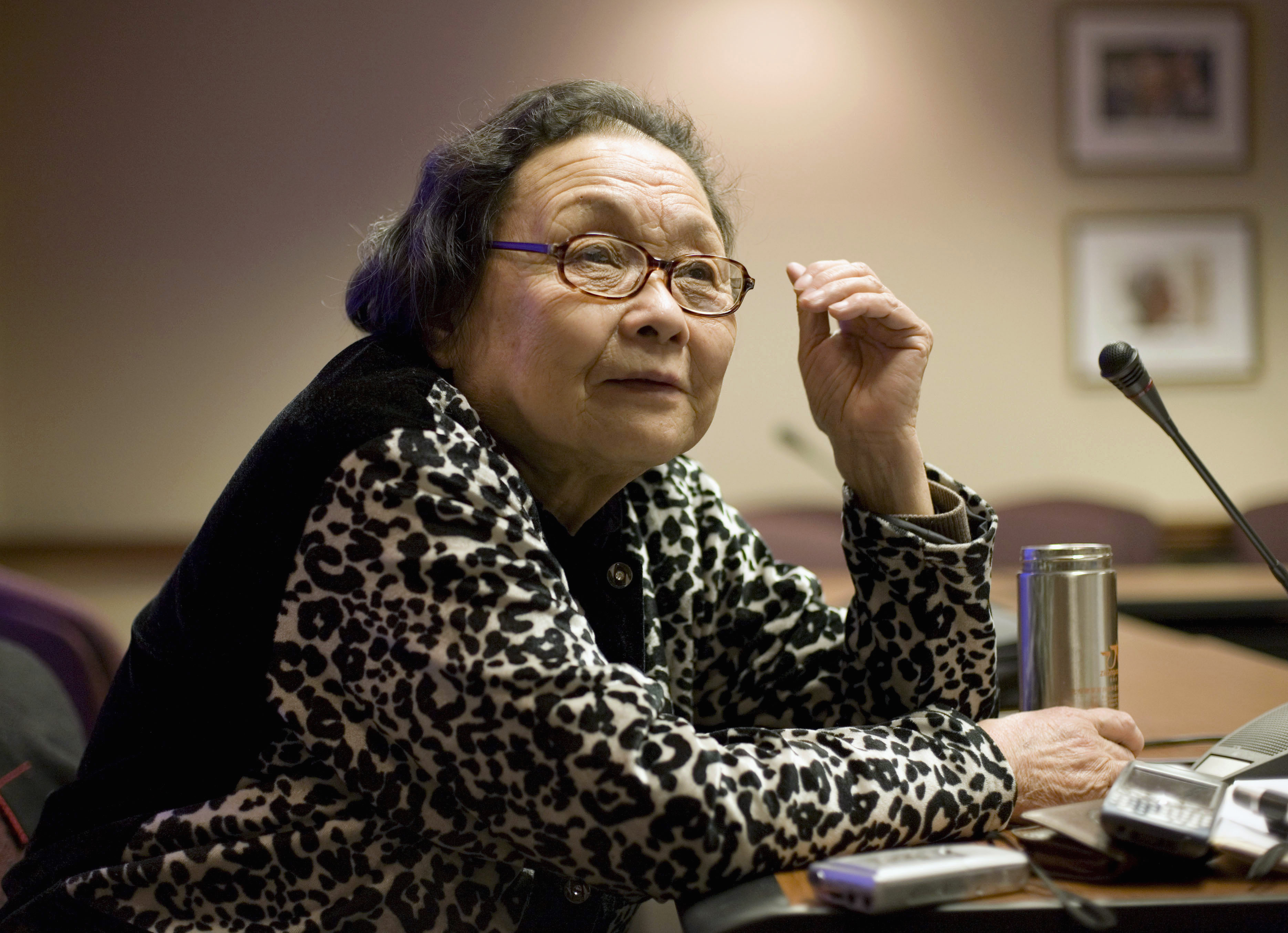 Gao Yaojie. She is pictured at the age of 80. She is seated at a desk. She looks relaxed