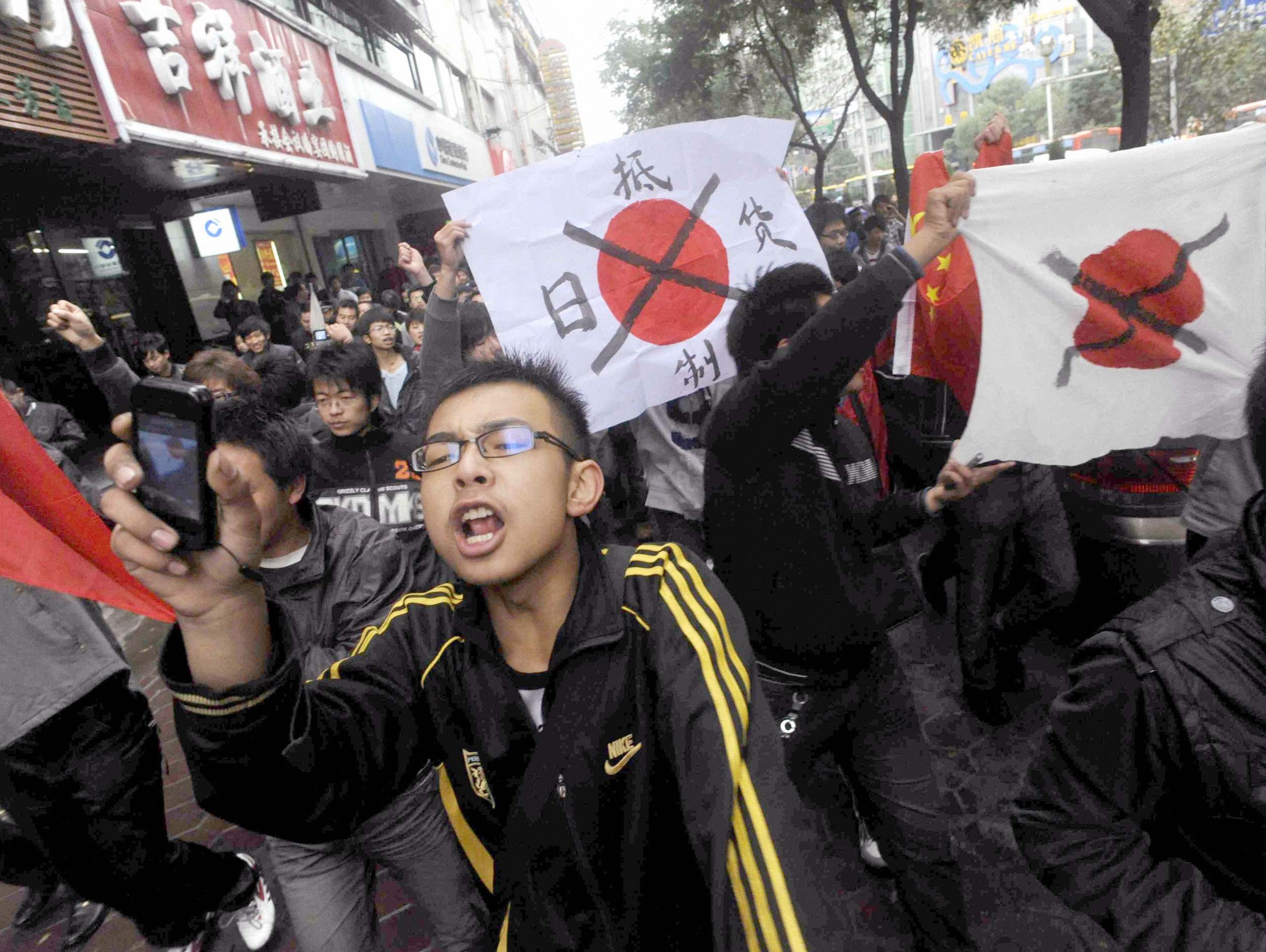 Protesters hold defaced Japanese flags during an anti-Japan demonstration in Lanzhou, Gansu province October 24, 2010. Chinese police on Sunday broke up protests against Japan in the northwestern city of Lanzhou over a territorial dispute that has stoked tensions between Asia's two biggest economies. REUTERS/Kyodo (CHINA - Tags: CIVIL UNREST POLITICS) FOR EDITORIAL USE ONLY. NOT FOR SALE FOR MARKETING OR ADVERTISING CAMPAIGNS. JAPAN OUT. NO COMMERCIAL OR EDITORIAL SALES IN JAPAN. THIS IMAGE HAS BEEN SUPPLIED BY A THIRD PARTY. IT IS DISTRIBUTED, EXACTLY AS RECEIVED BY REUTERS, AS A SERVICE TO CLIENTS