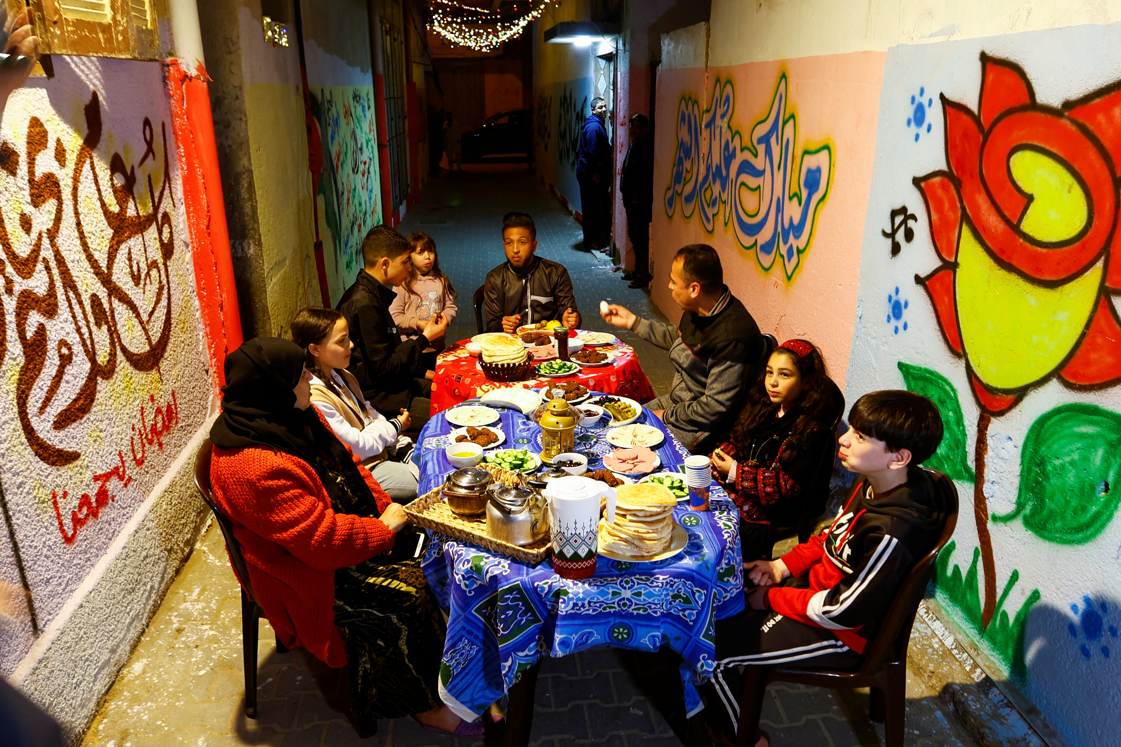 Palestinians eat their predawn meal next to a house before they start their day-long fast, during the holy month of Ramadan, in Khan Younis, southern Gaza Strip March 25, 2023. REUTERS/Ibraheem Abu Mustafa