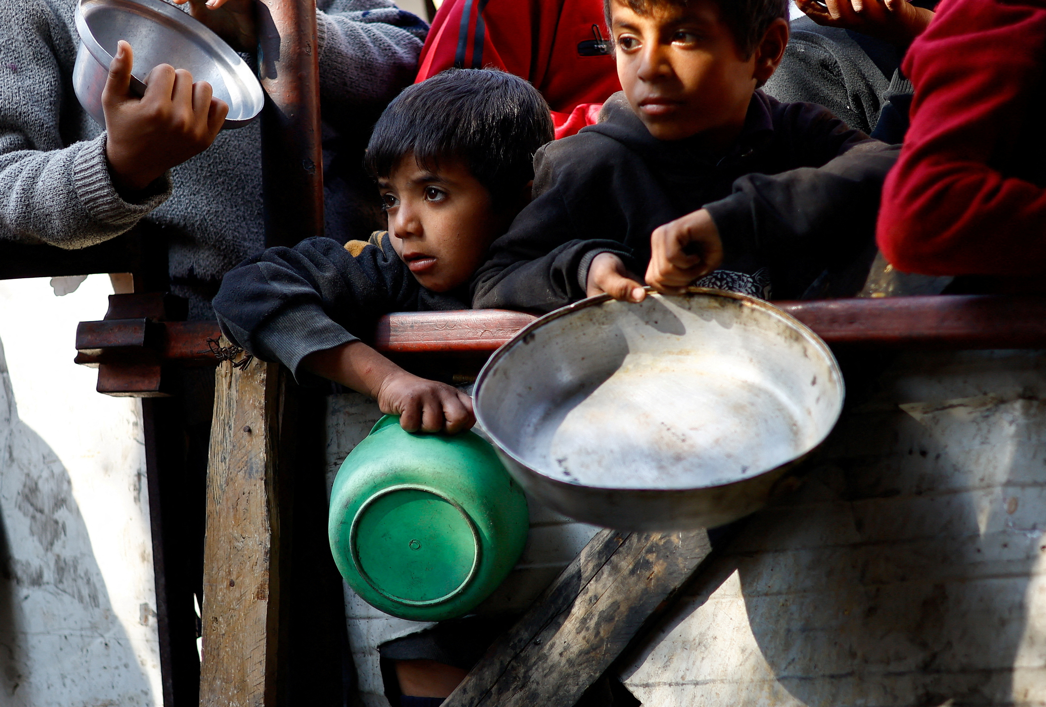 Palestinians wait to receive food cooked by a charity kitchen amid shortages of food supplies, amid the ongoing conflict between Israel and the Palestinian Islamist group Hamas, in Rafah in the southern Gaza Strip, January 16, 2024