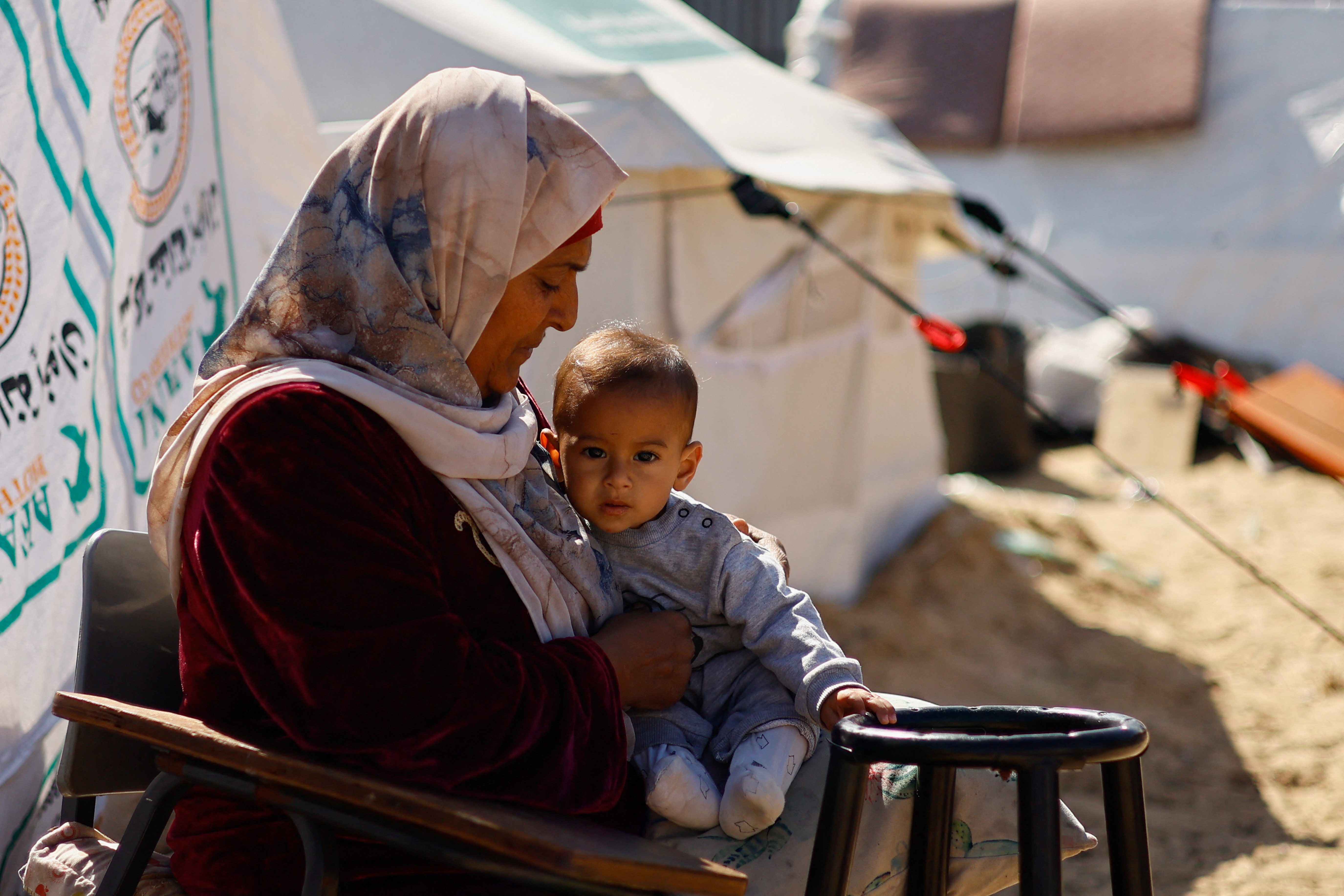 A woman holds a baby as displaced Palestinians, who fled their houses due to Israeli strikes take shelter at the border with Egypt, amid the ongoing conflict between Israel and the Palestinian Islamist group Hamas, in Rafah in the southern Gaza Strip, February 15, 2024