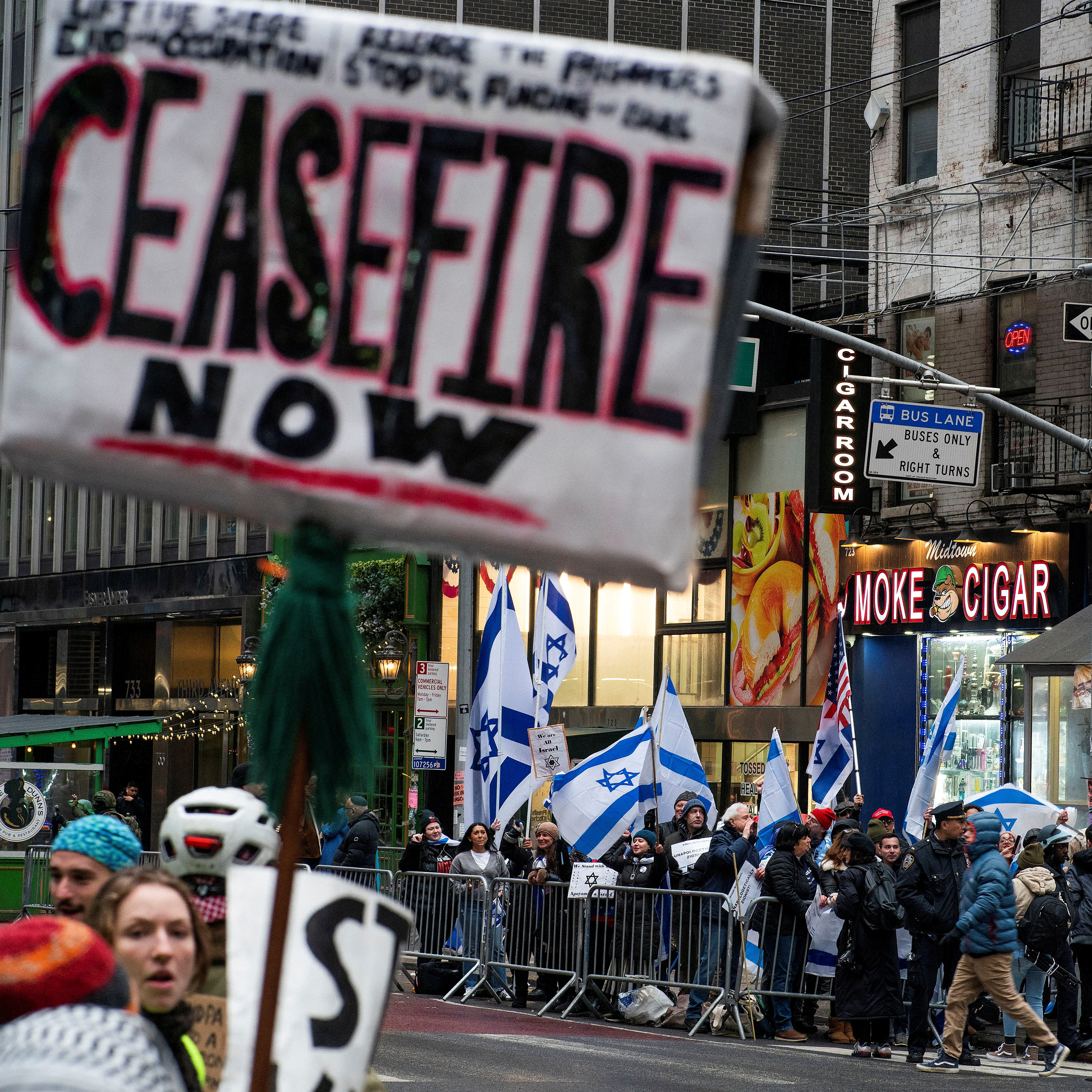 People hold Israeli flags as protesters hold a rally in front of the AIPAC offices demanding a ceasefire