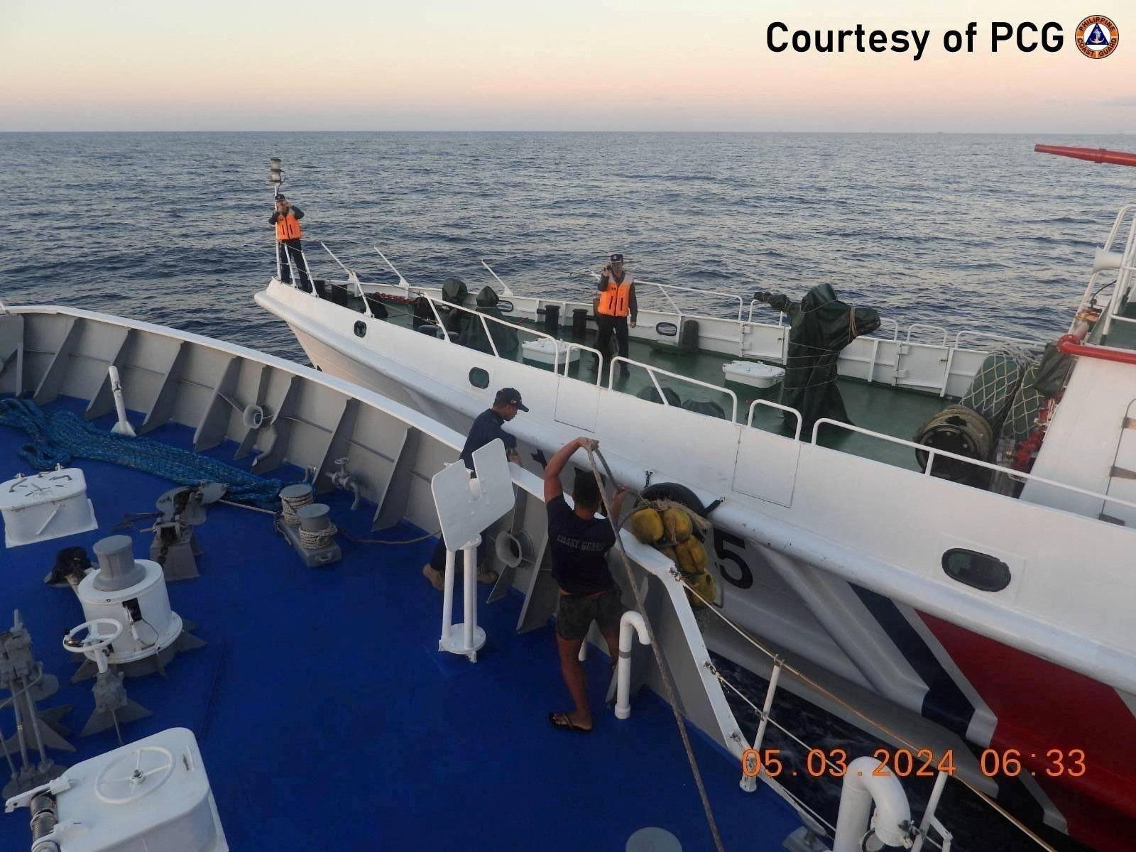 Crew members of a Philippine coast guard ship at the bow after a Chinese coast guard vessel cut into its path