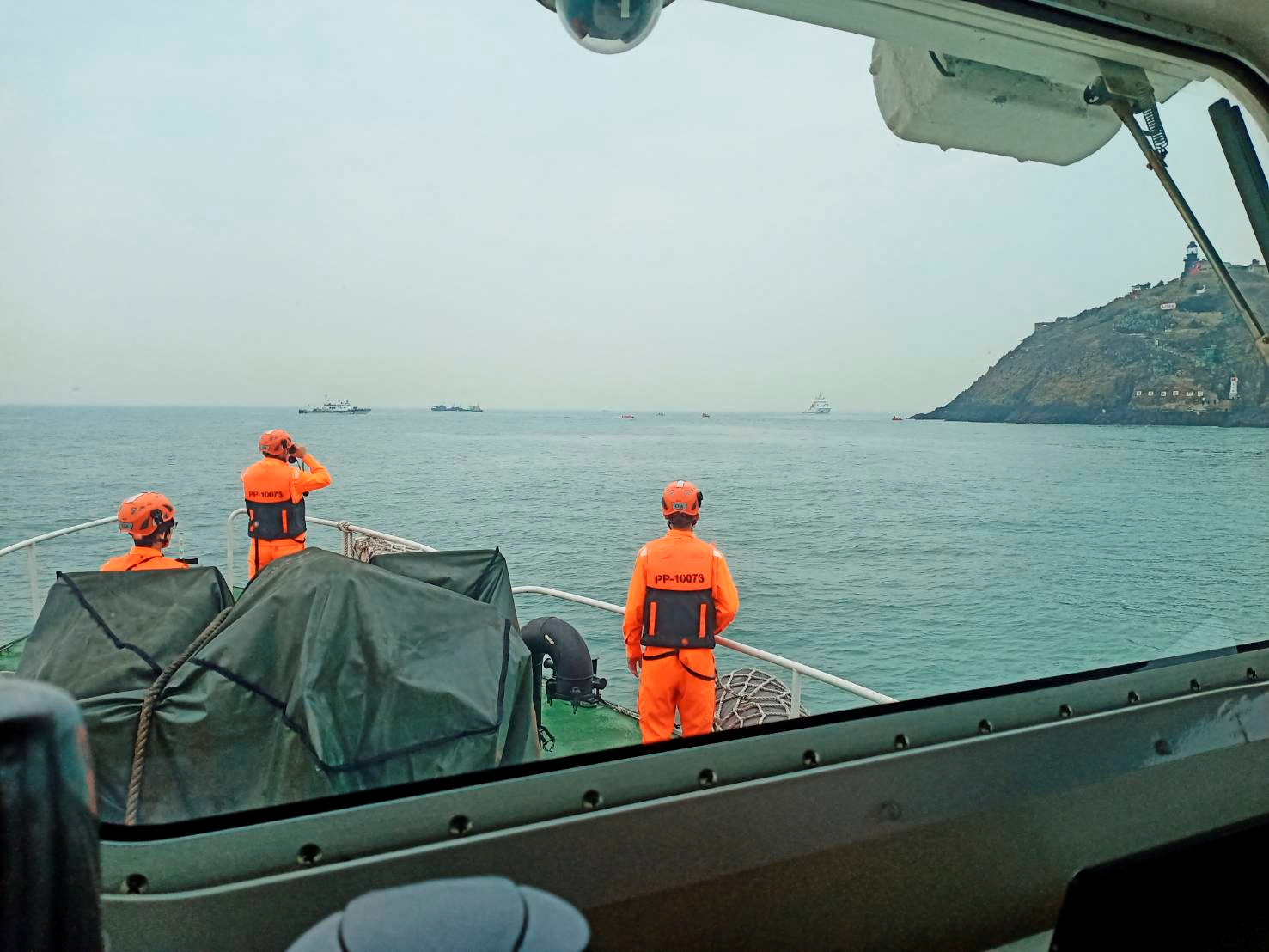 Members of Taiwan's coast guard during the rescue mission. They are wearing high-vis suits and standing on the deck. The sea looks calm.