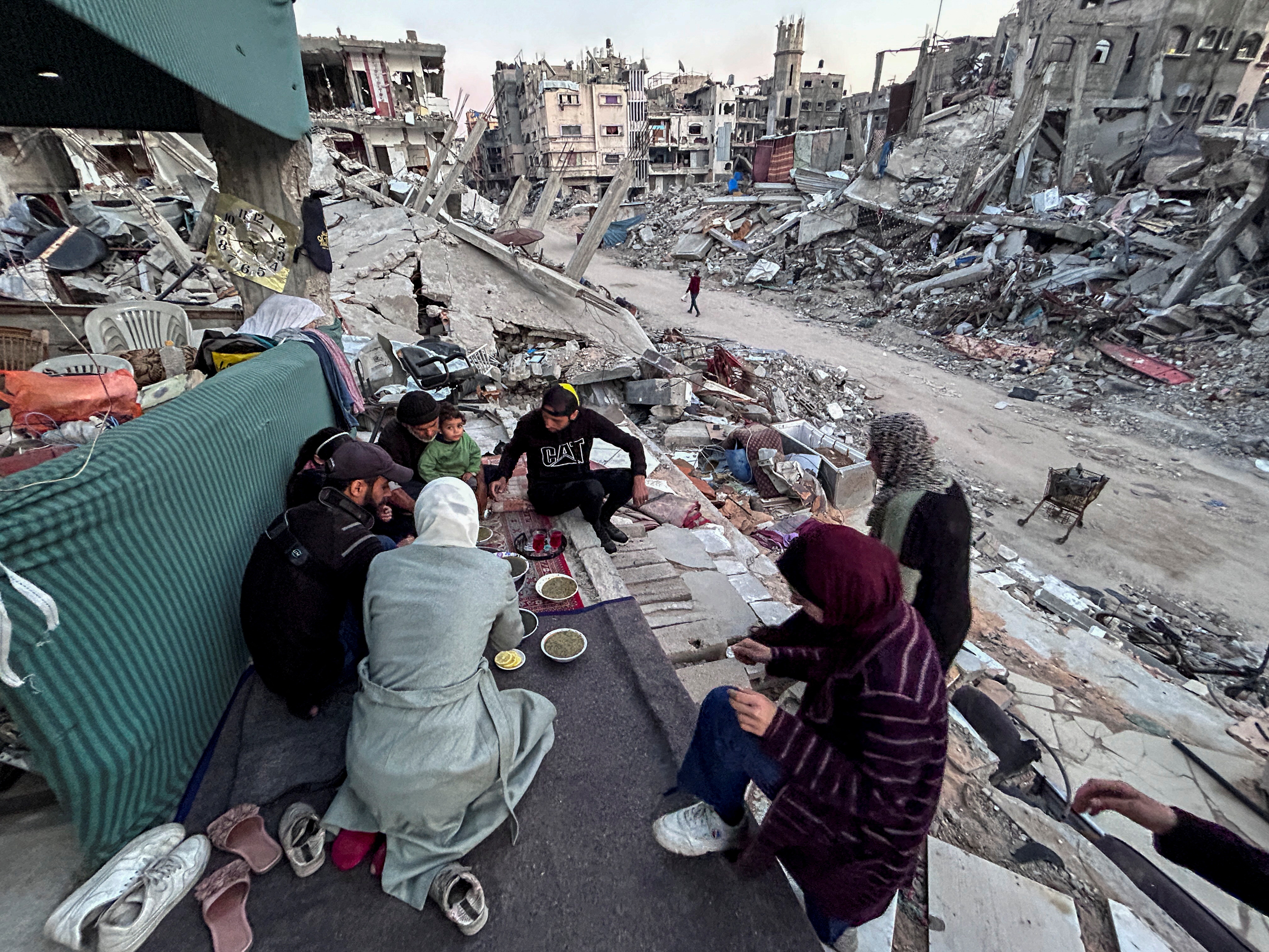 Palestinian members of Al-Khlout family break their fast on the rubble of their house which was destroyed during Israel's military offensive, during the holy month of Ramadan, as the conflict between Israel and Hamas continues, in Beit Lahia in the northern Gaza Strip, March 13, 2024. REUTERS/Mahmoud Issa
