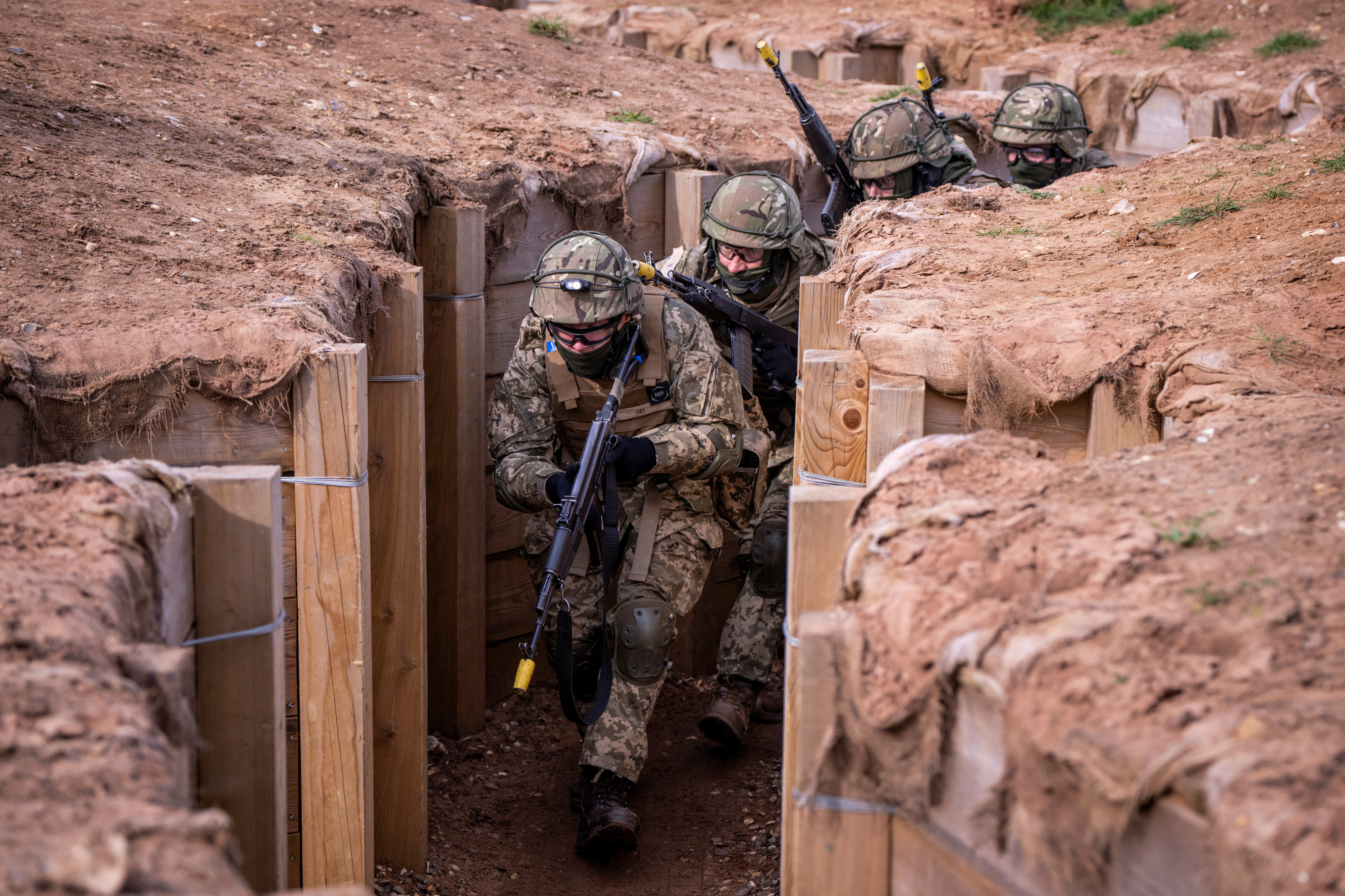 Ukrainian soldiers moving through a trench on a training ground.