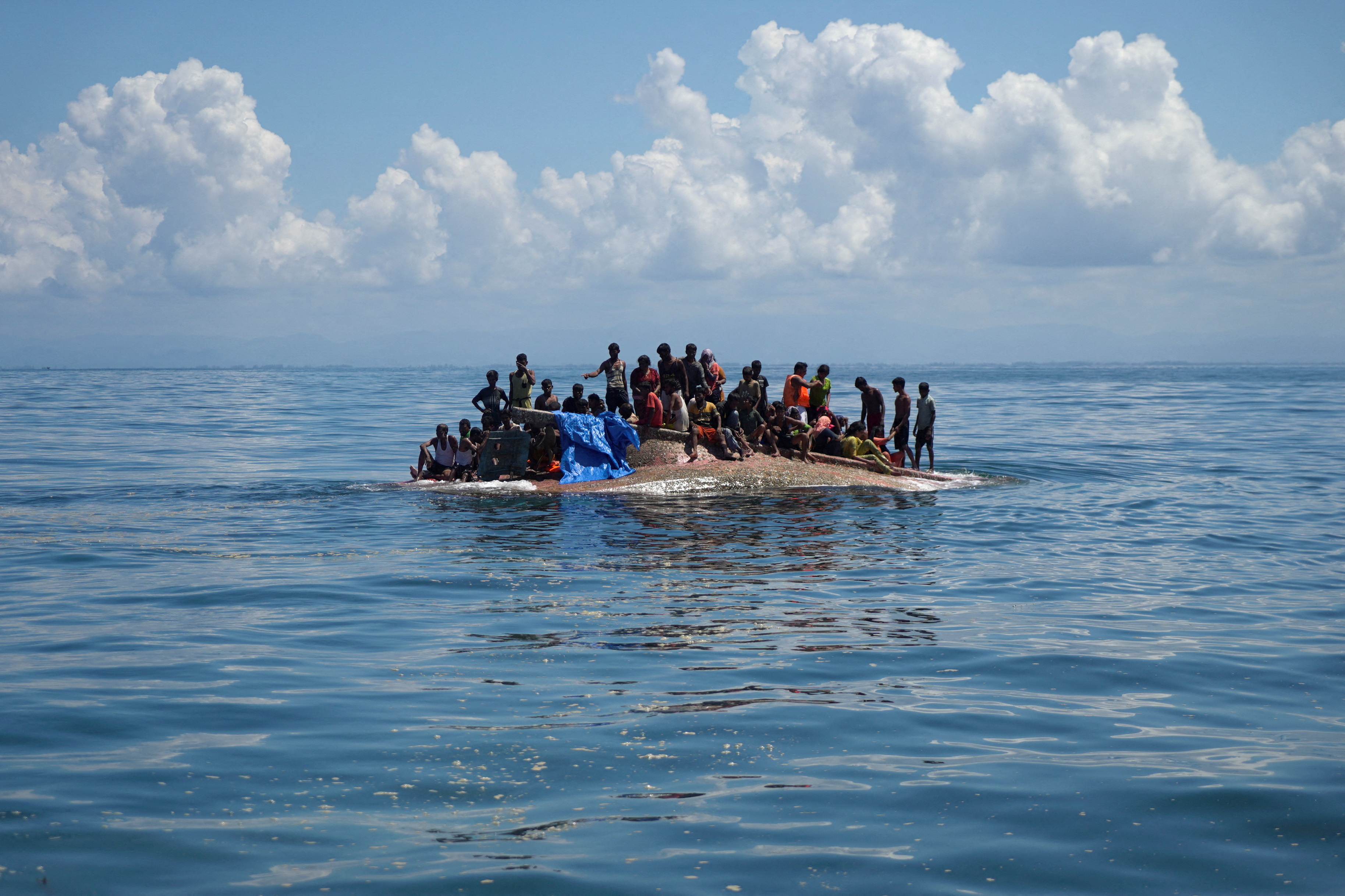 Rohingya refugees are seen on a capsized boat before being rescued in the waters of West Aceh, Indonesia, March 21
