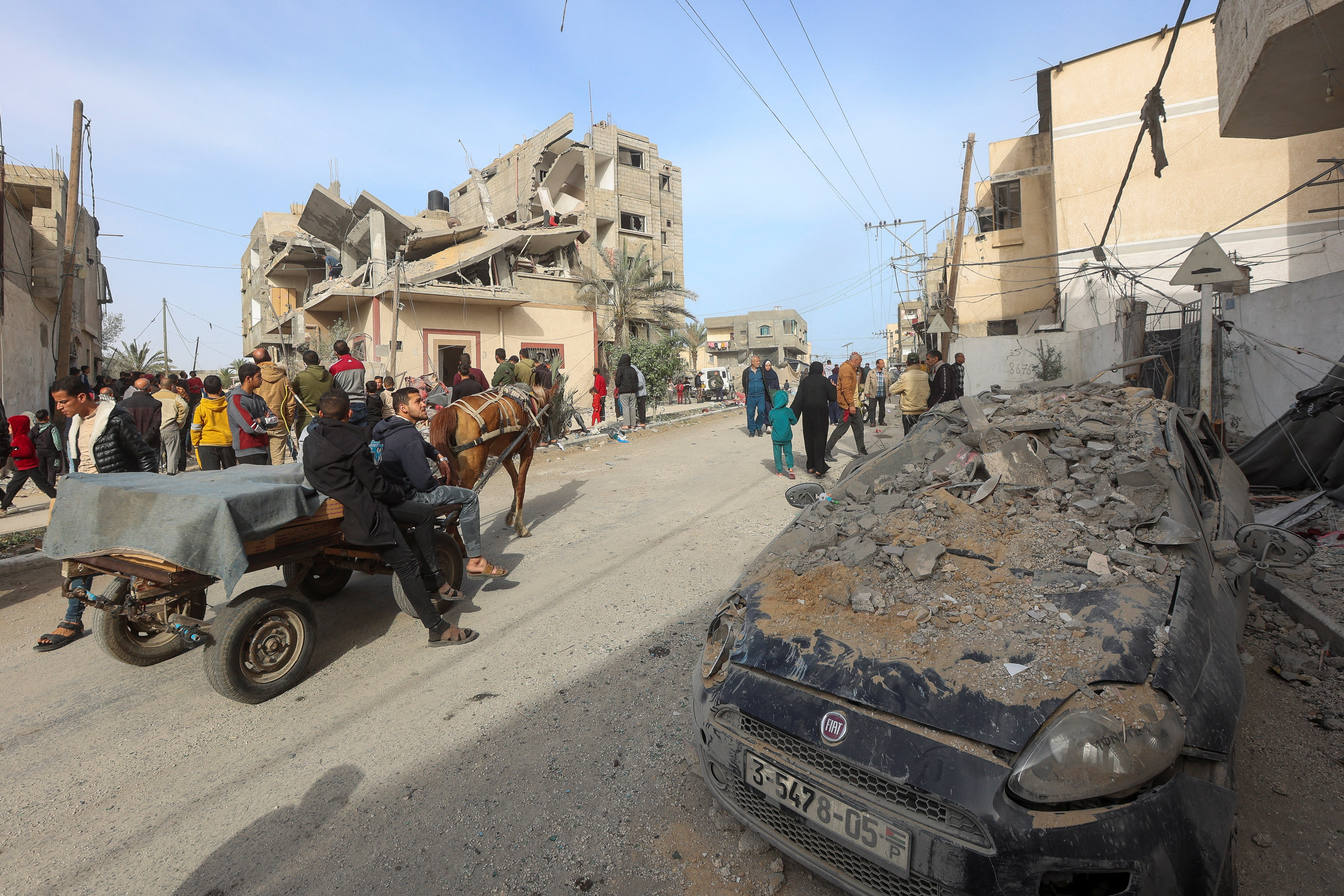 Palestinians ride a horse-drawn cart past the site of an Israeli strike on a house