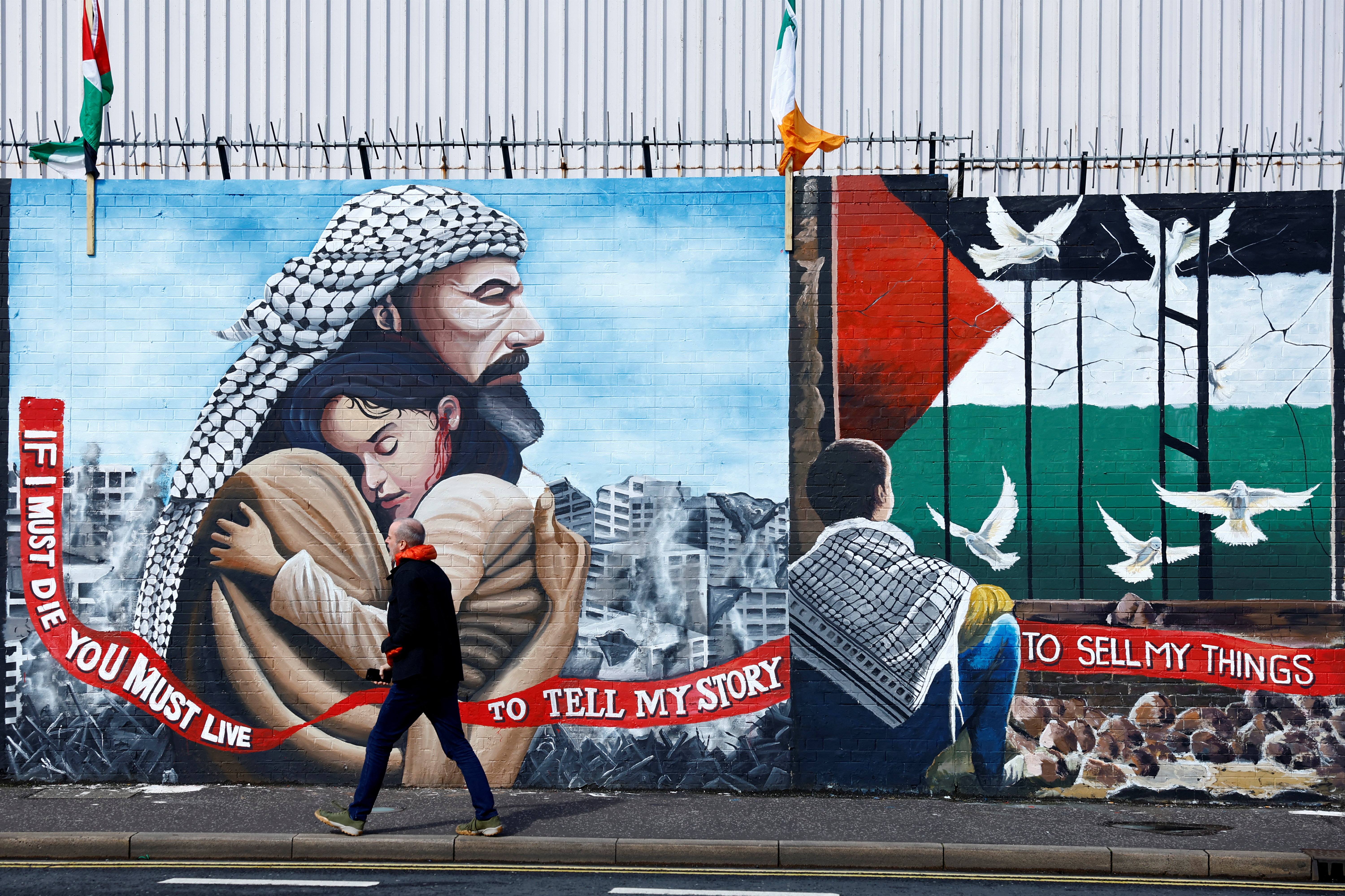 A man walks past pro-Palestinian murals on the International Wall in support of Gaza, amid the ongoing conflict between Israel and the Palestinian Islamist group Hamas, in Belfast, Northern Ireland