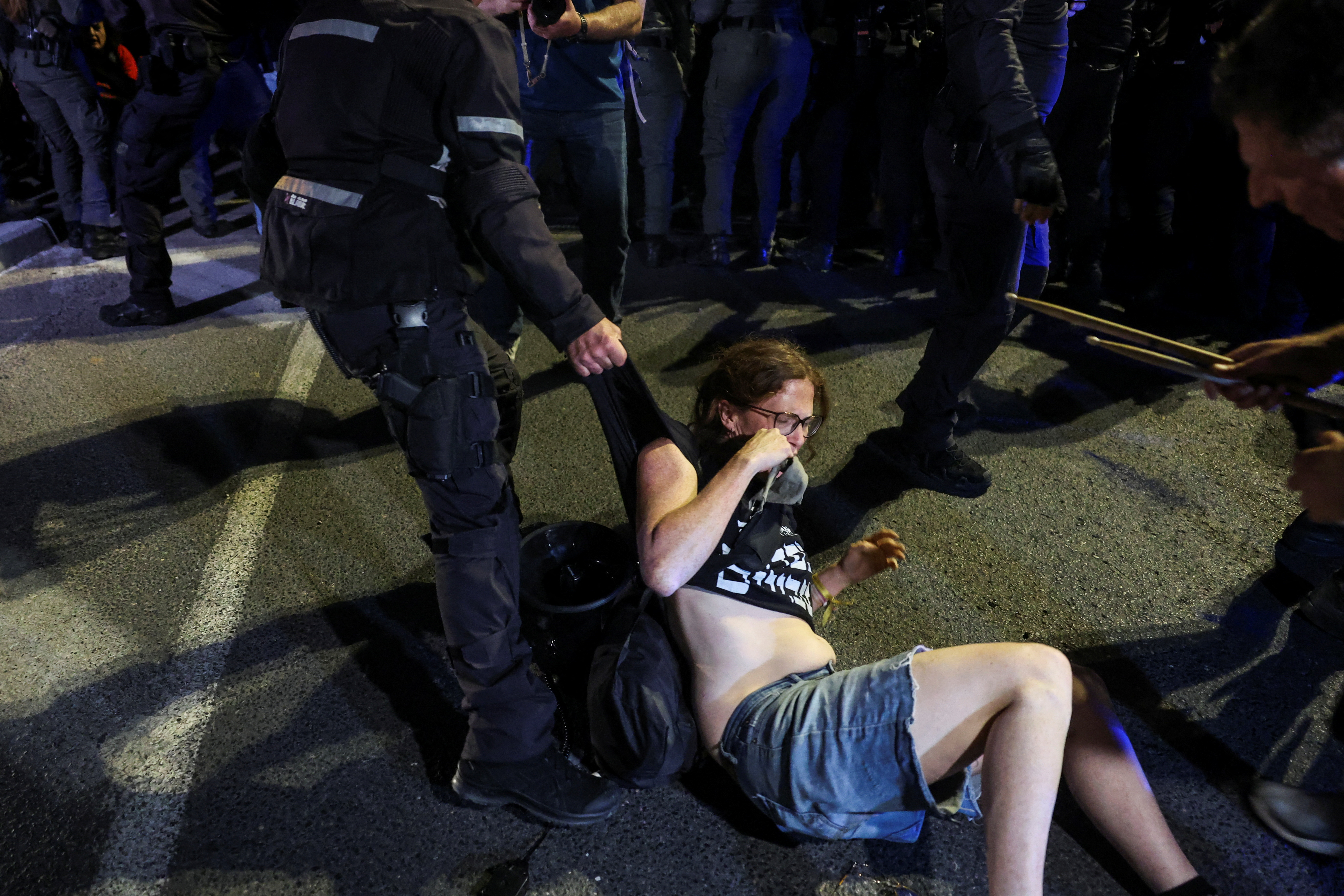 An officer holds a demonstrator's clothing as anti-government protesters launch a prolonged demonstration