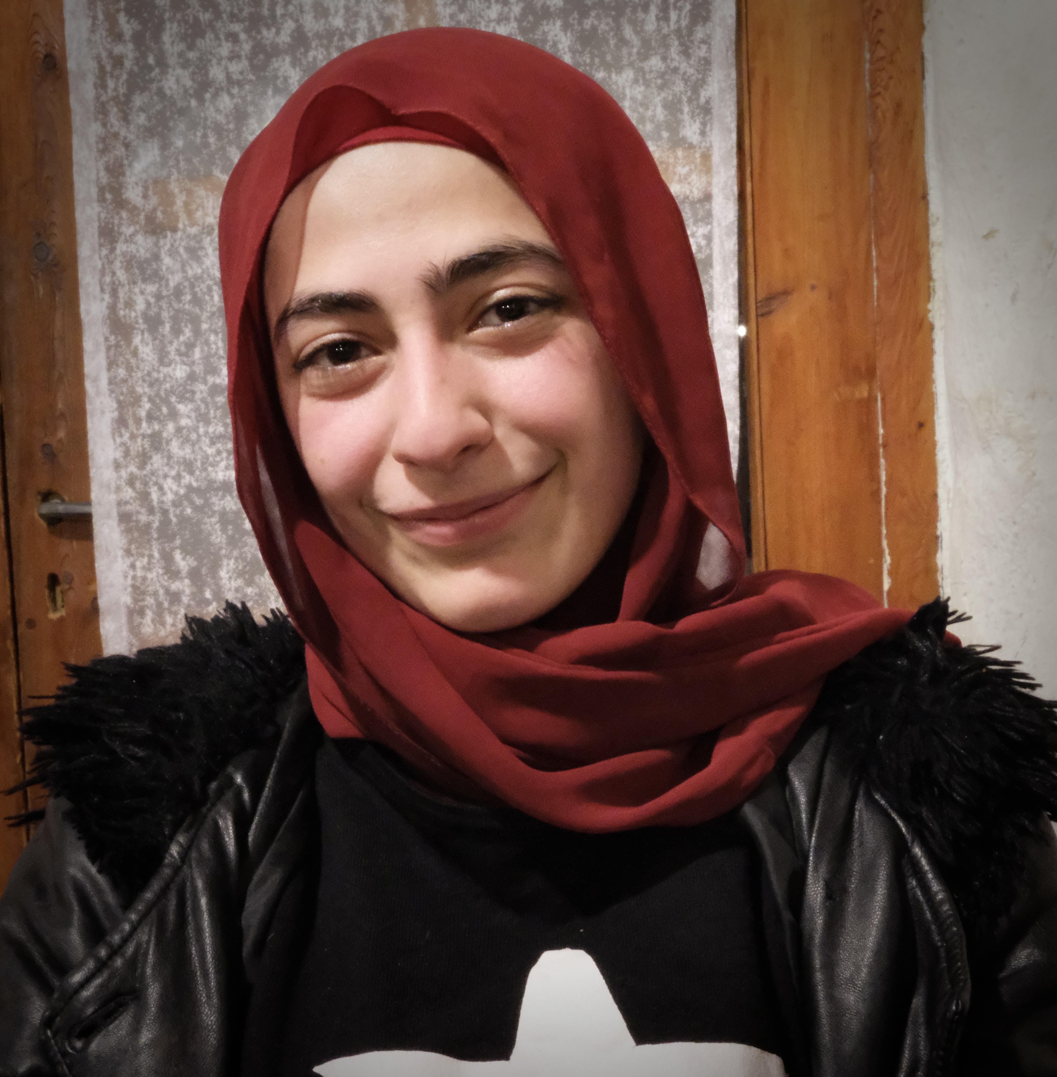 Close up of a teenage girl in a burgundy hijab and a black jacket
