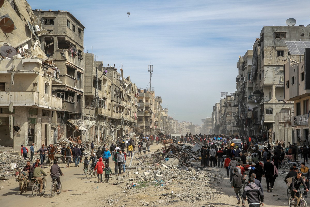 Palestinians gather in a street as humanitarian aid is airdropped in Gaza City