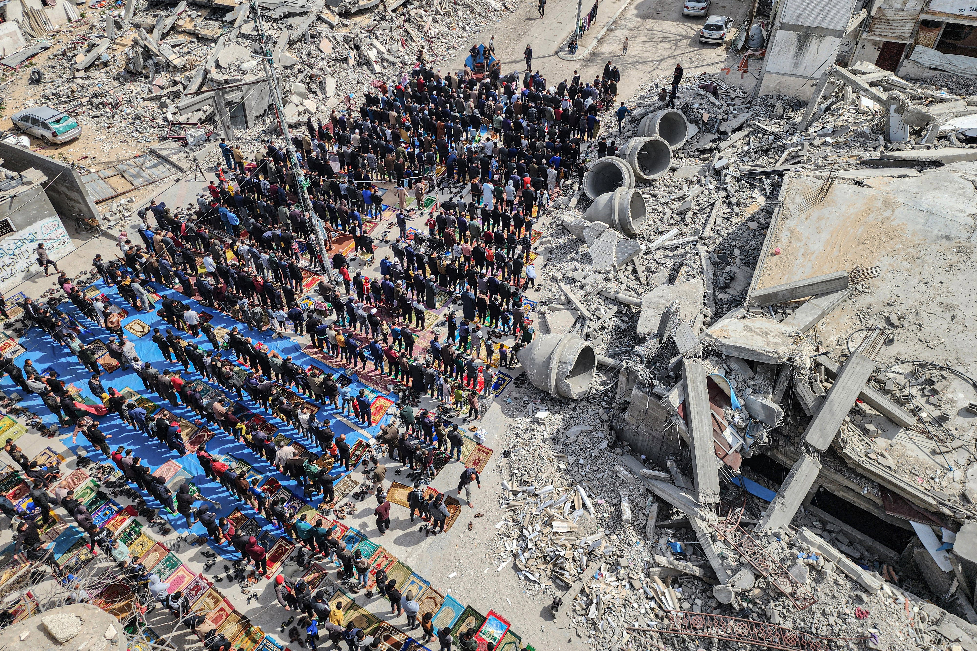 In this aerial view, Palestinians attend the Friday noon prayers in front of the ruins of the al-Faruq mosque, destroyed in Israeli strikes in Rafah in the southern Gaza Strip on March 1, 2024, amid continuing battles between Israel and the Palestinian militant group Hamas. (Photo by SAID KHATIB / AFP)