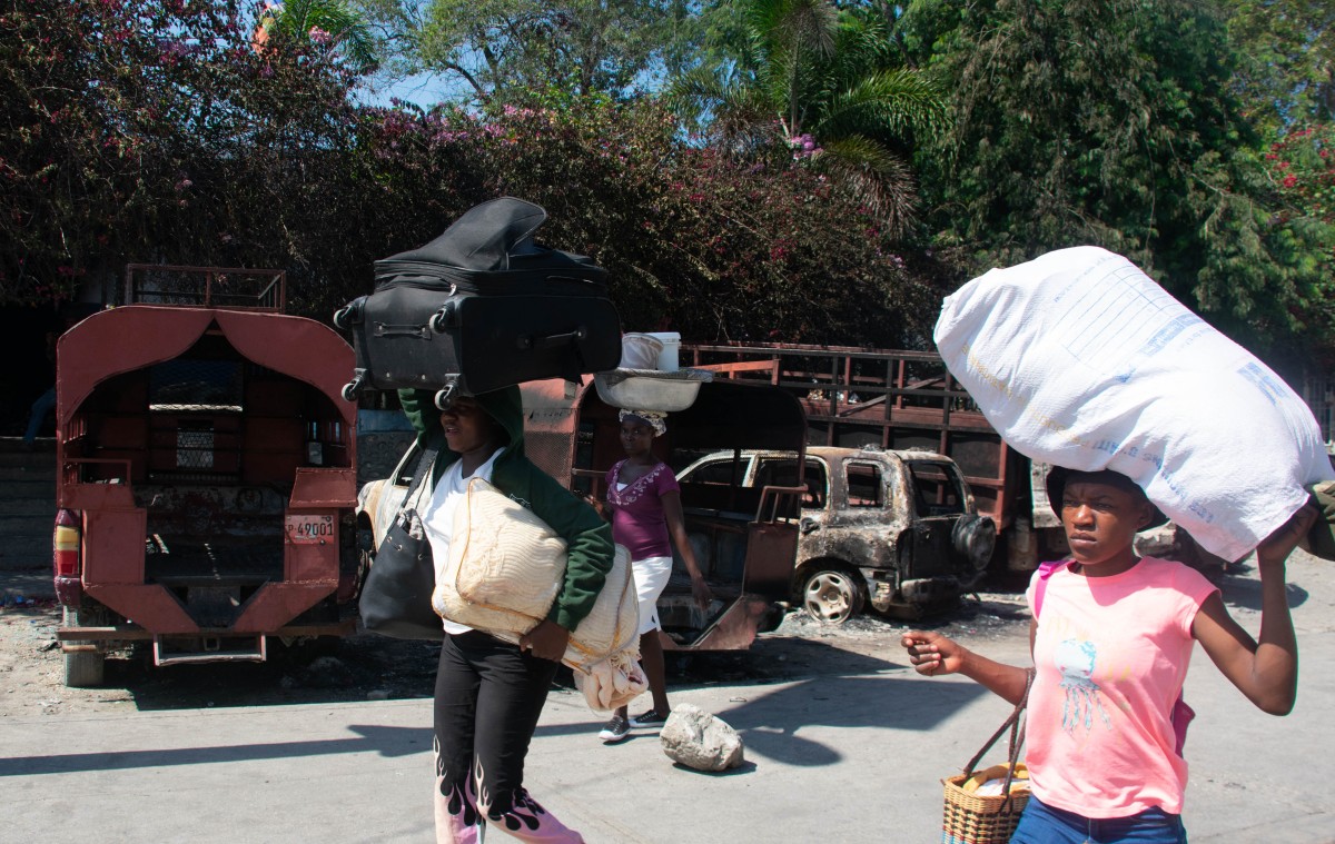 People are seen carrying their belongings as they leave the city