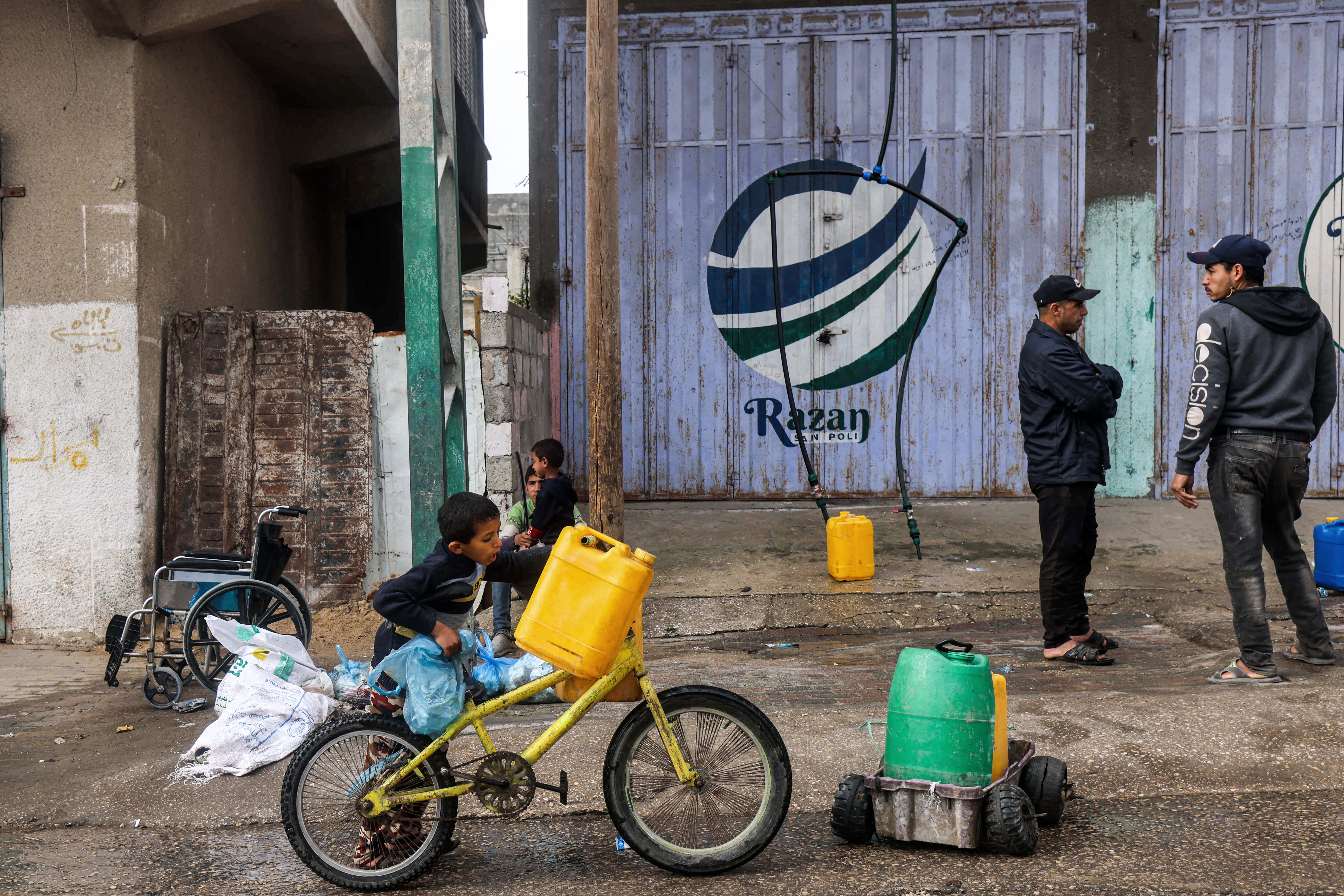 A boy places a jerrycan on the handlebar of a bicycle in Rafah