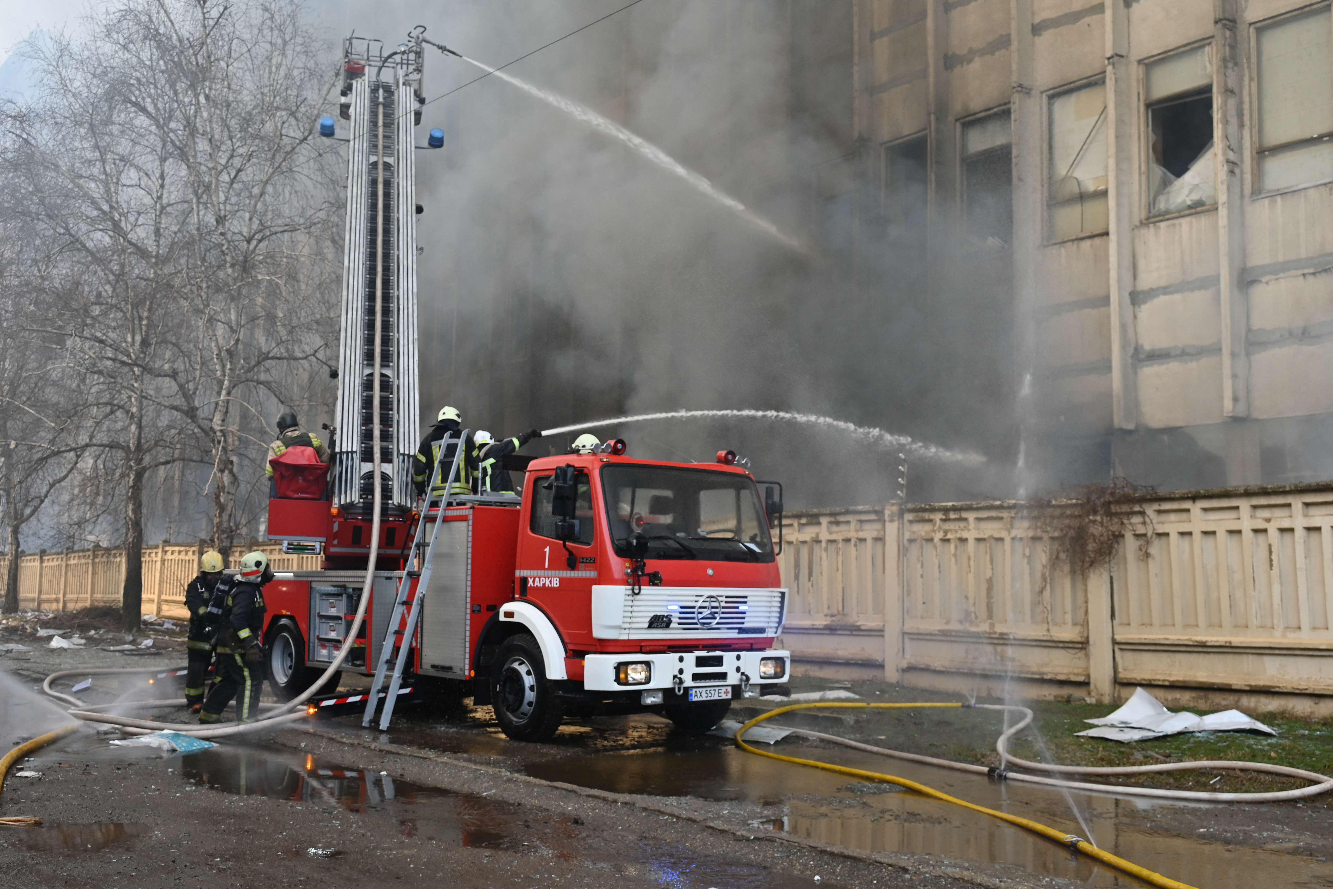 A fire engine at the scene of a printing works fire caused by a Russian missile attack. There is lots of smoke.. Firemen are directing the hoses from the truck.