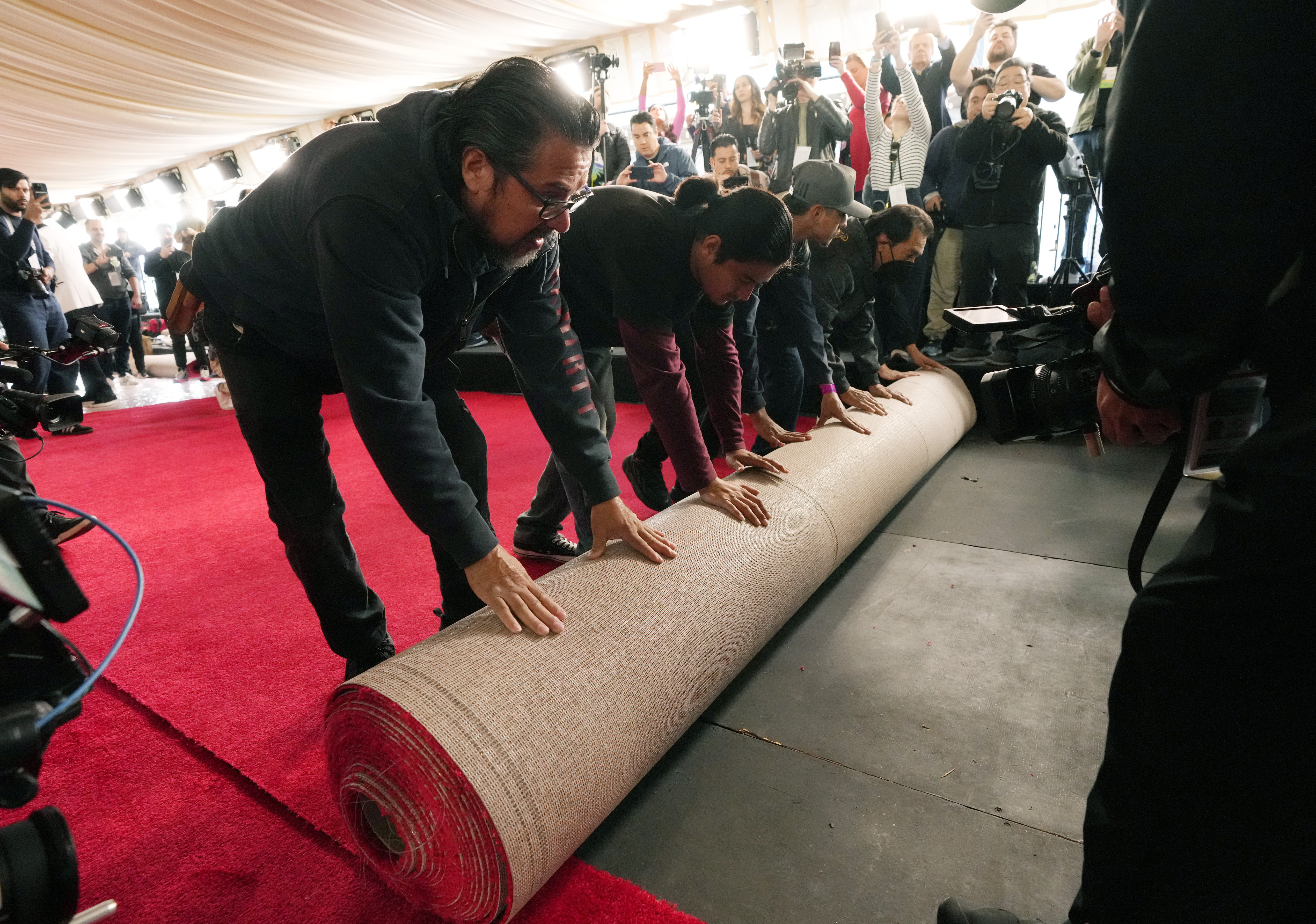 Crew members unfurl a roll of red carpet at the site of the 96th annual Academy Awards.