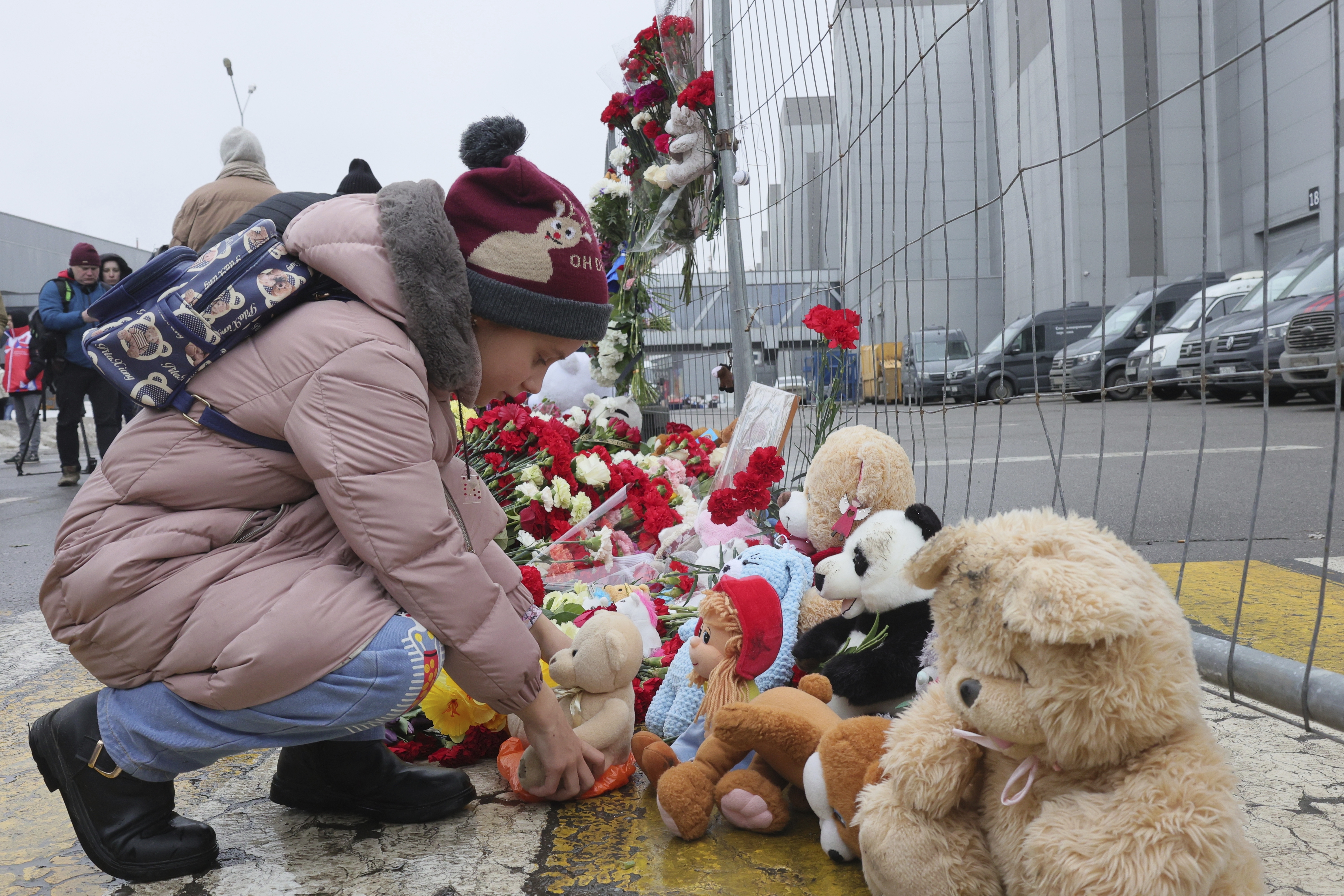 A child places a toy at the fence next to the Crocus City Hall, on the western edge of Moscow, Russia, Saturday, March 23