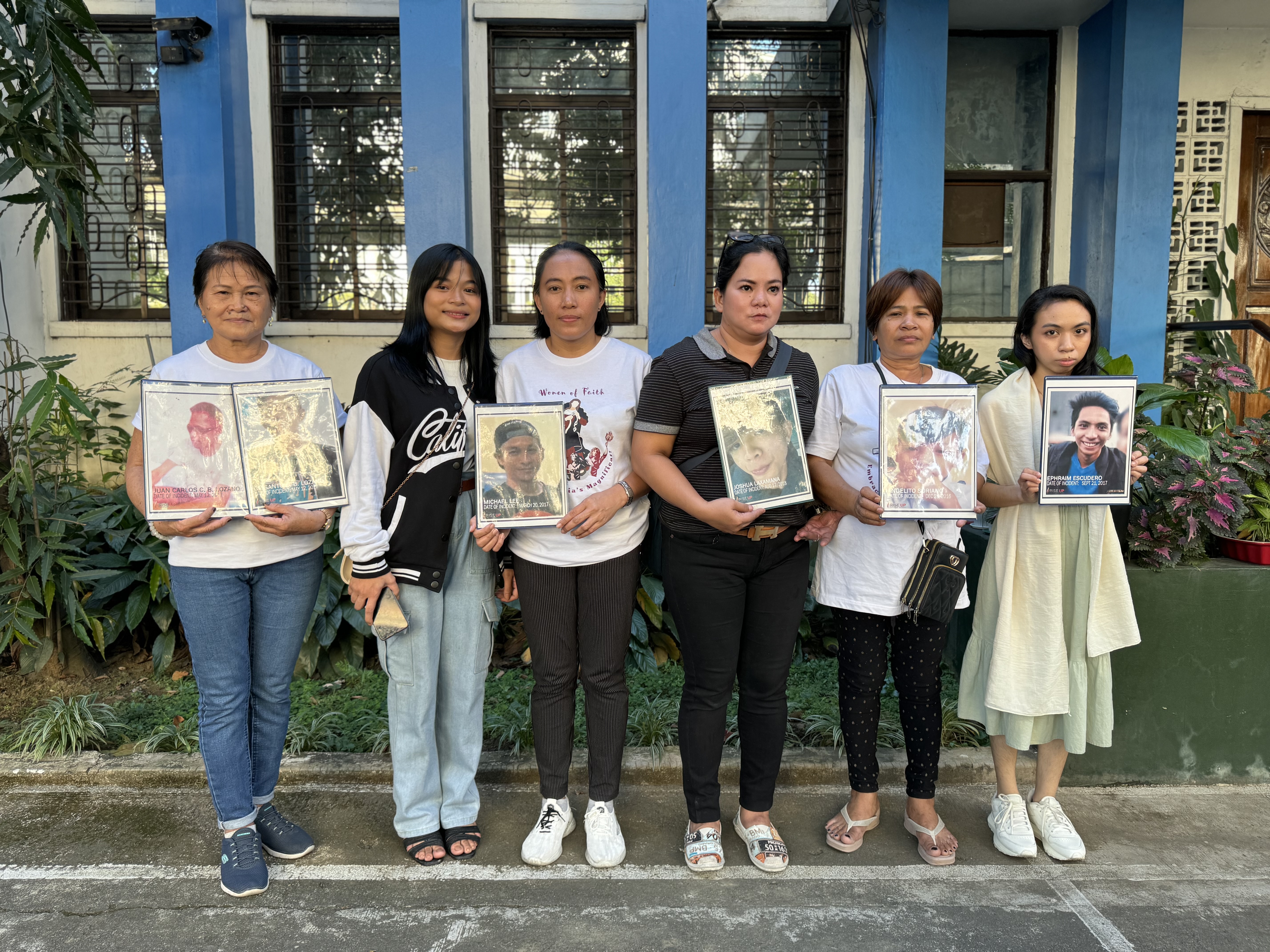 Women from Rise Up. They are holding photos of people killed in the drug war 