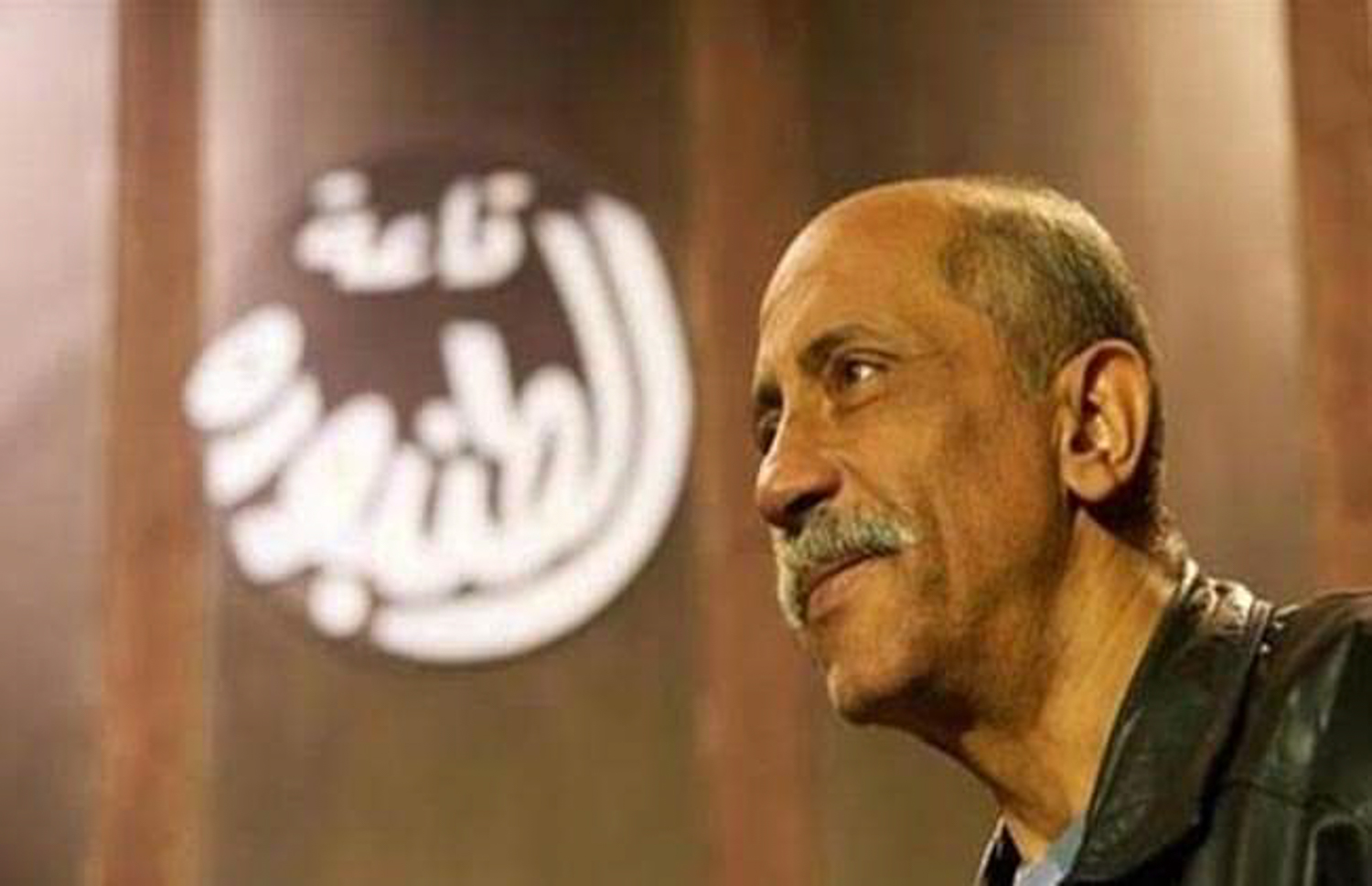 Smiling Zakaria against an out-of-focus background with name of hall