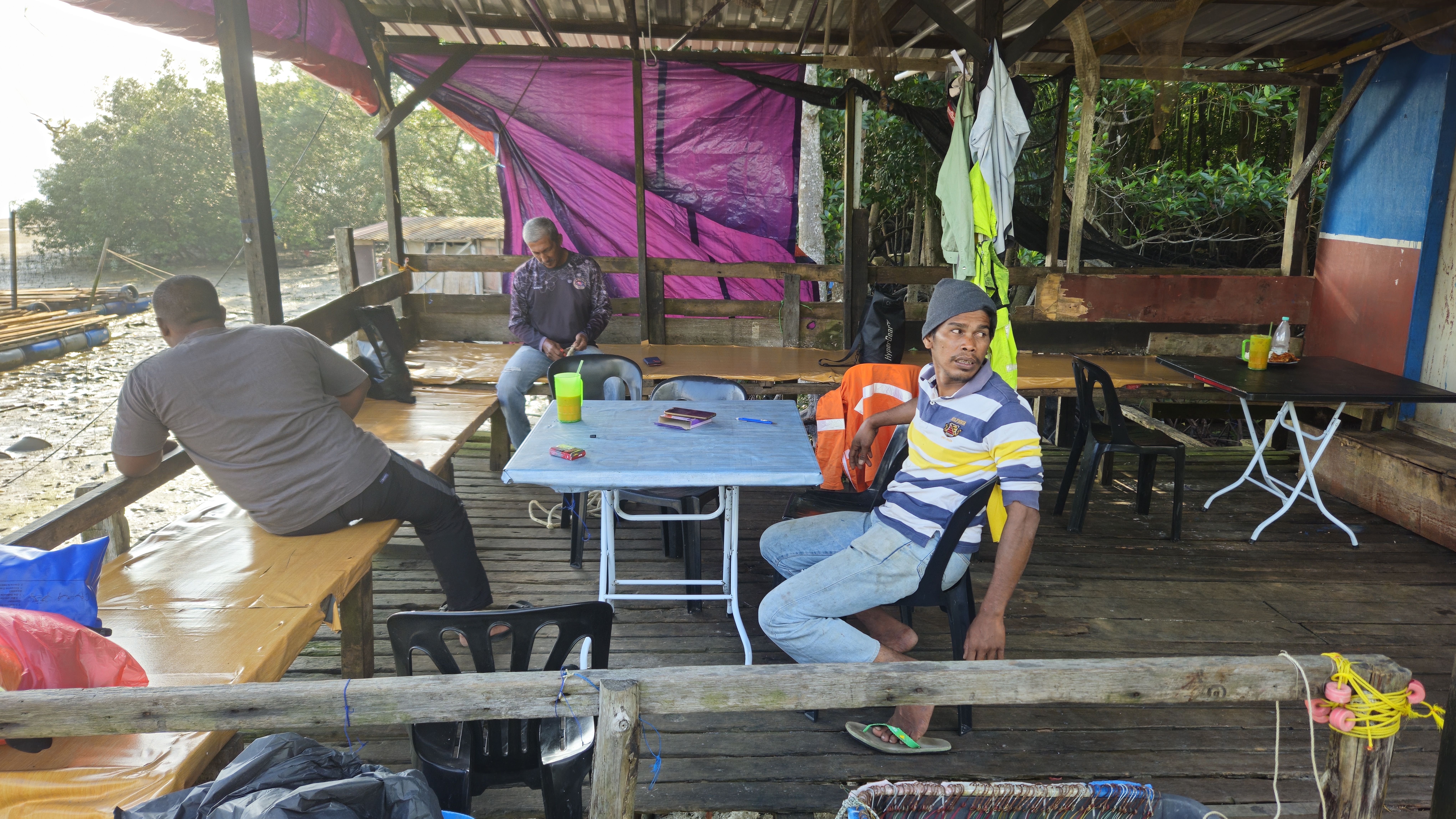 Fishermen resting in a shelter on the coast near the jetty in Pendas. The sea and mudflats can seen to one side.