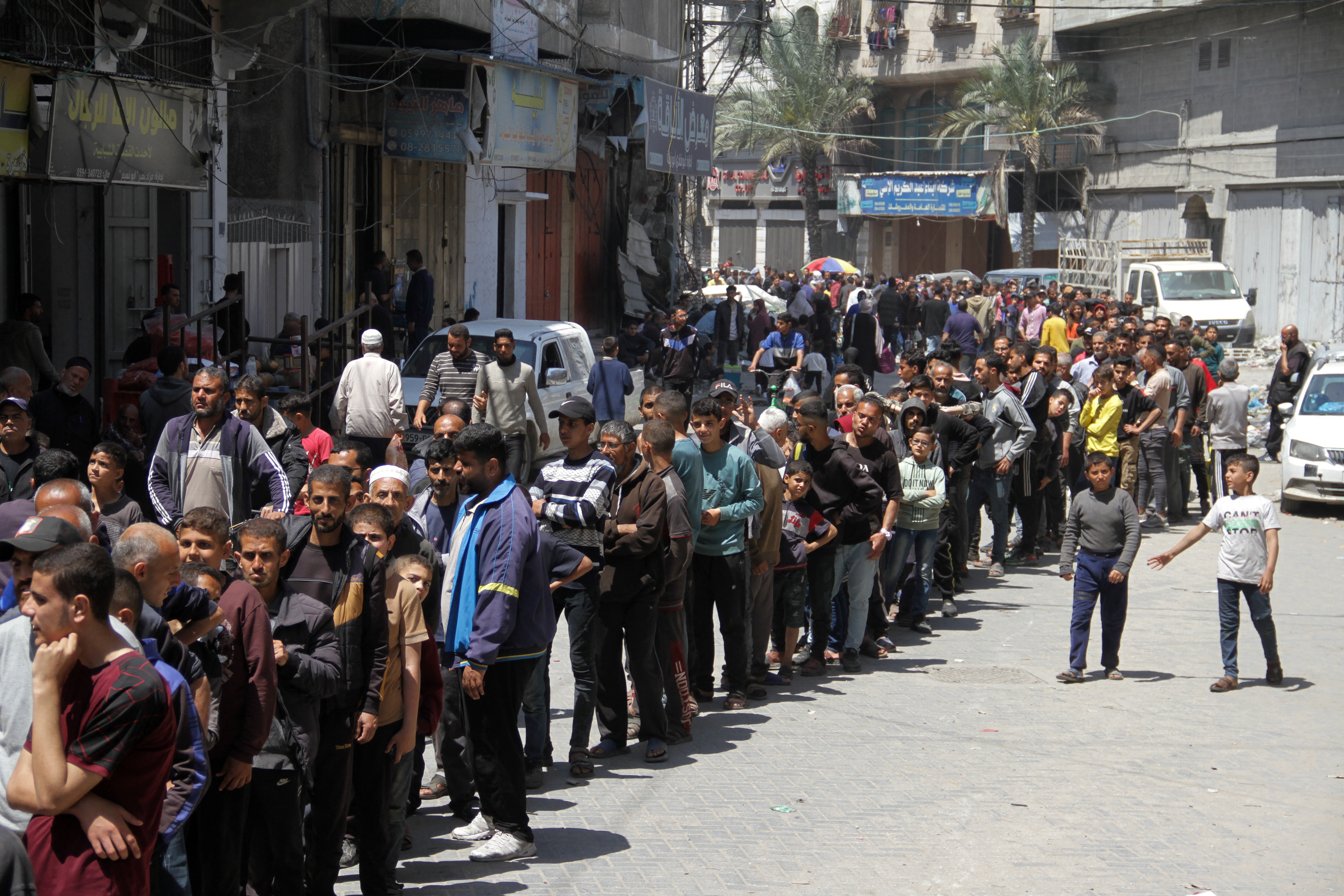 Palestinians gather to buy bread from a bakery which went back into service after being shut down for several months