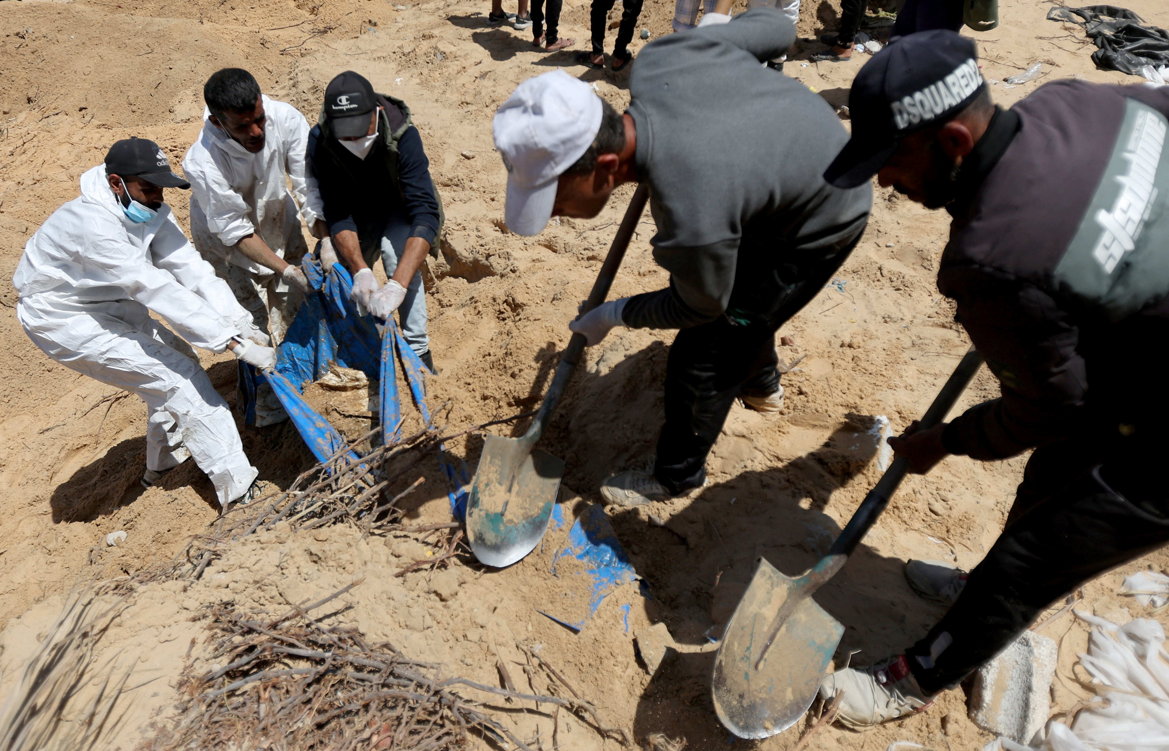 People work to move into a cemetery bodies of Palestinians killed during Israel's military offensive and buried at Nasser hospital, amid the ongoing conflict between Israel and the Palestinian Islamist group Hamas, in Khan Younis in the southern Gaza Strip, April 21