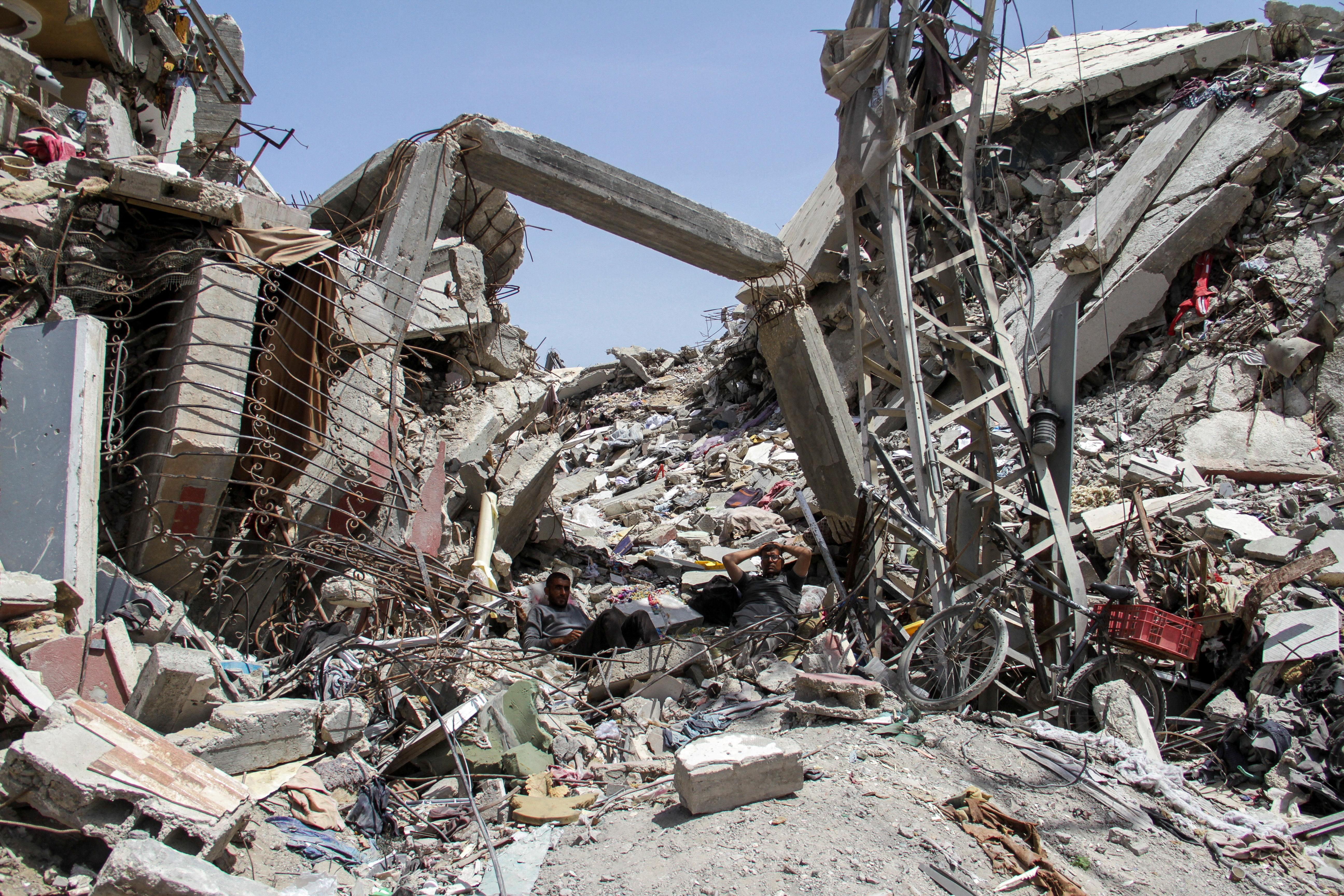 Palestinians rest at the rubble of a residential building 