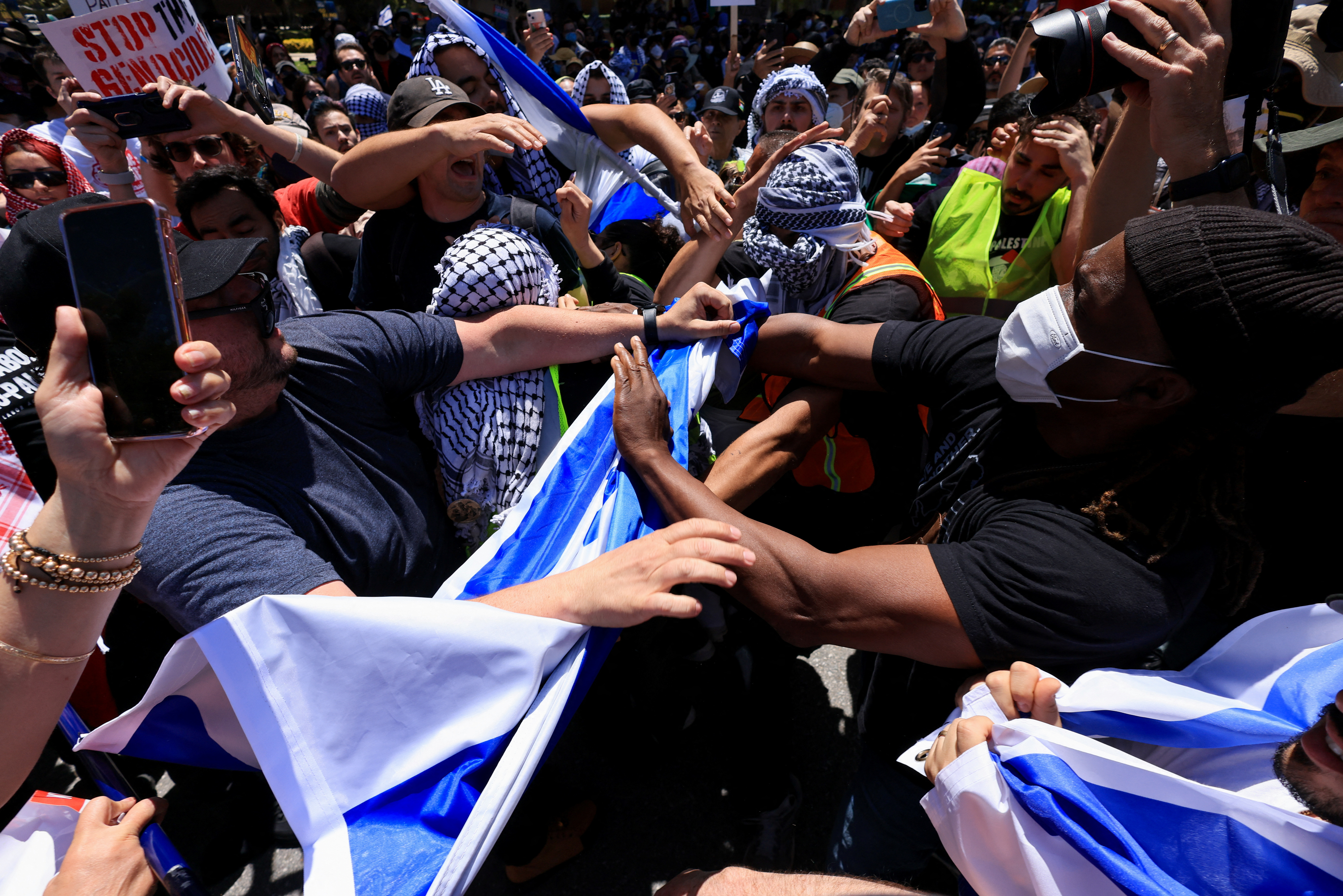 Pro-Palestinian and Pro-Israel protesters grapple with each other at UCLA. Some are pulling at each other. Some have grabbed an Israeli flag