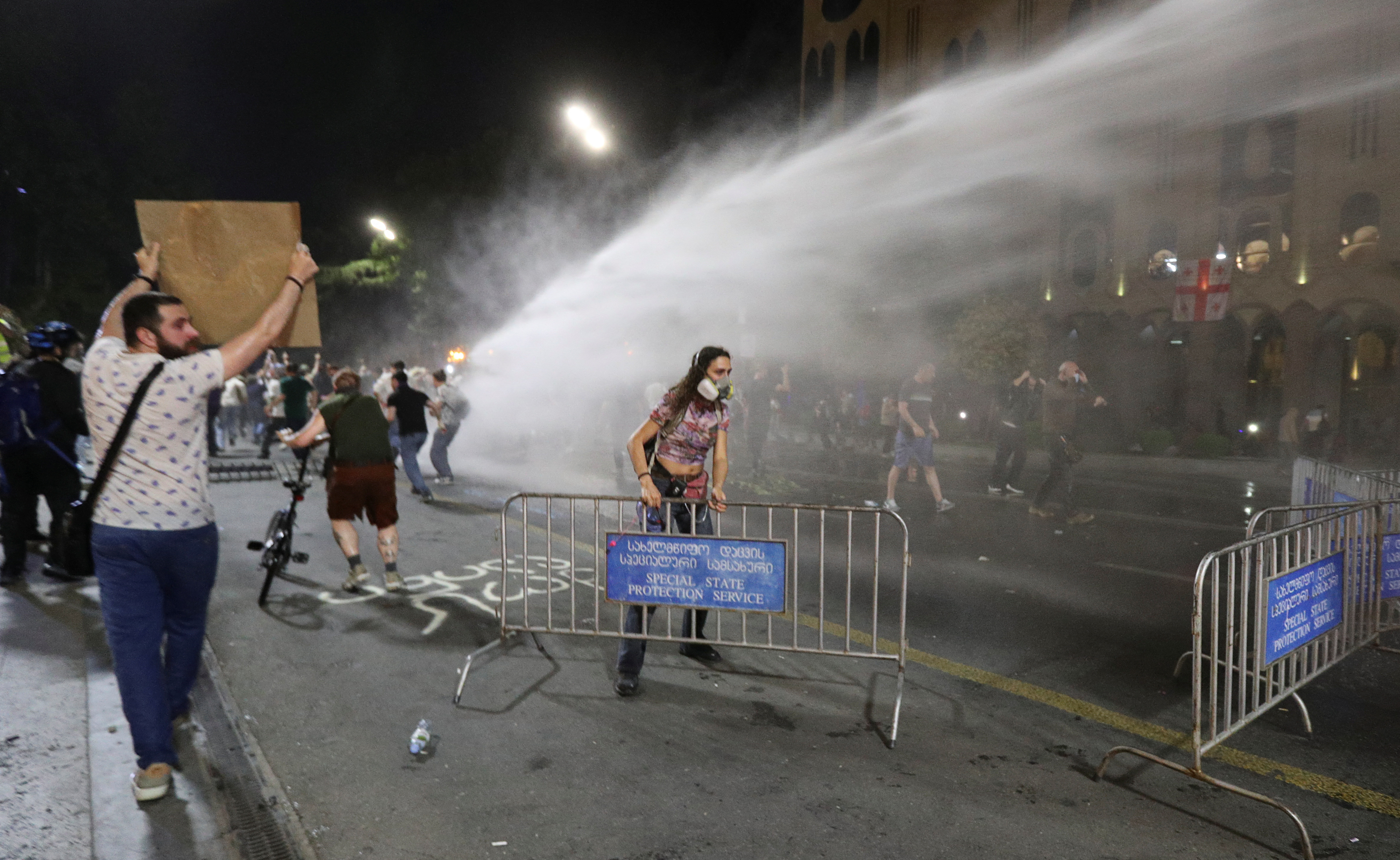 Law enforcement officers use a water cannon to disperse the crowd near the parliament building